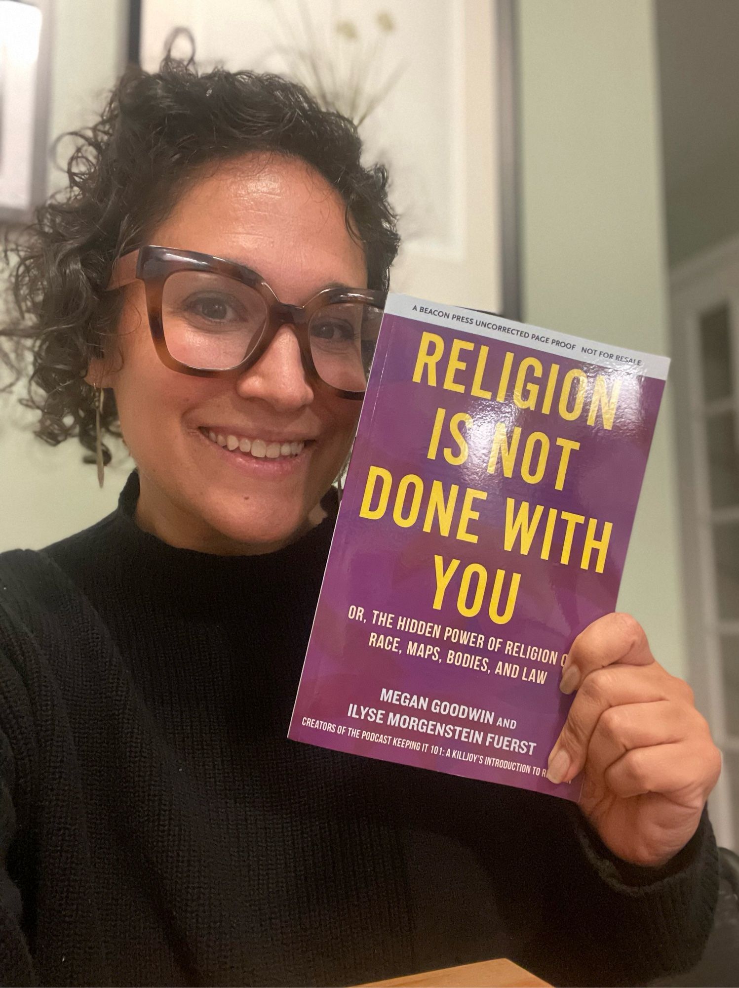 Image of a woman, Ilyse, with a book that is purple with yellow lettering. Title reads. Religion is not done with you. From beacon press.