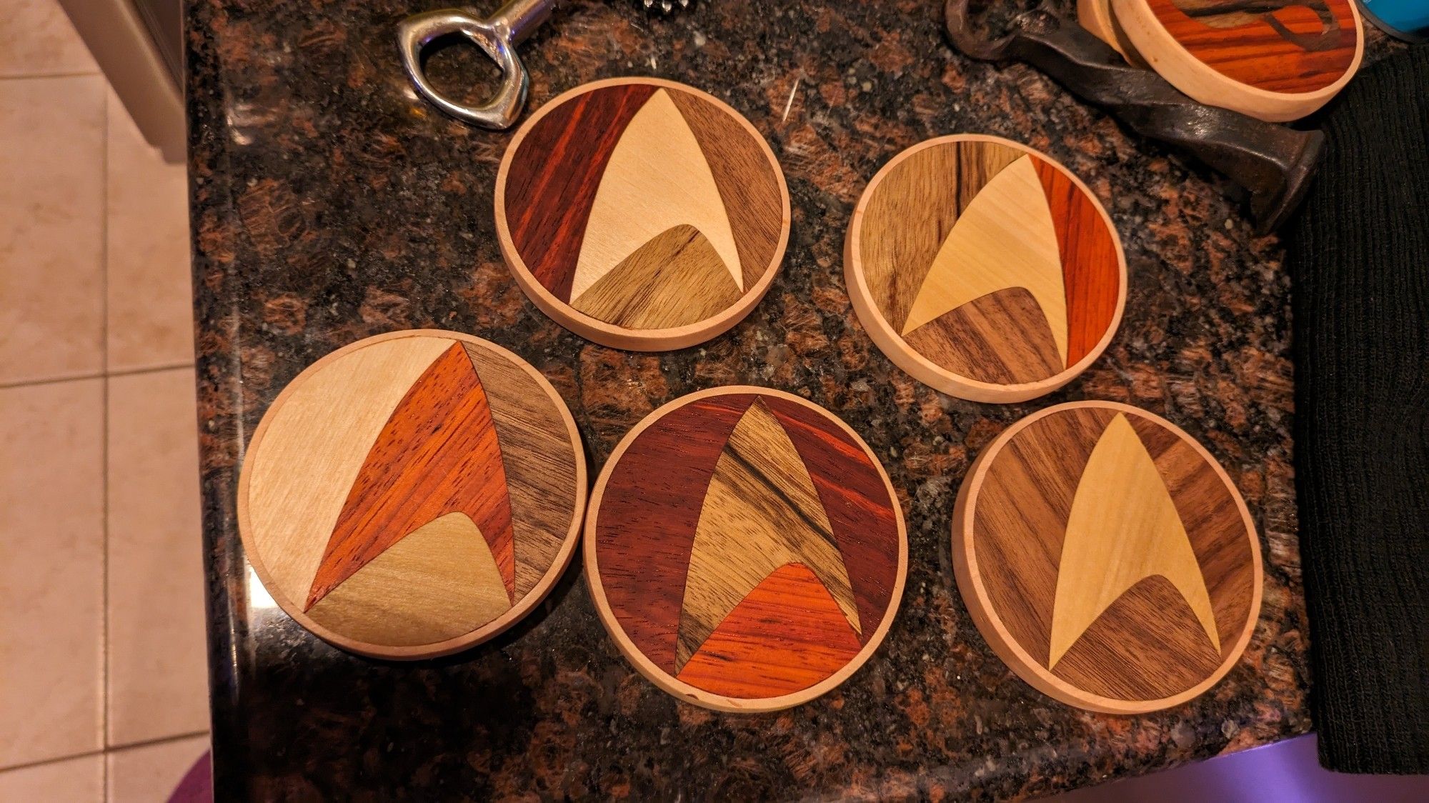 Several coasters made of various woods with a star trek logo