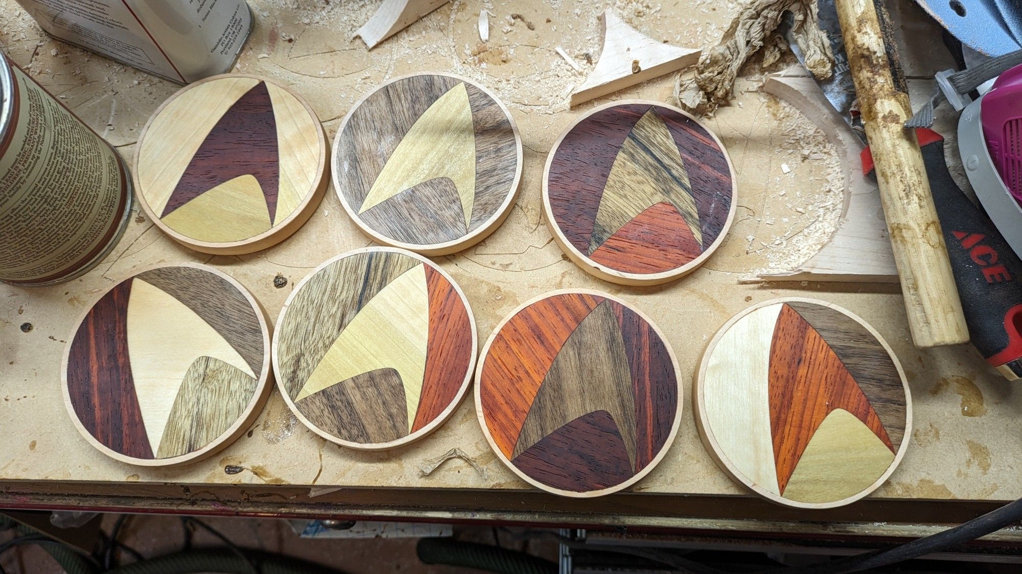 Several coasters with star trek logos, made of different woods on a workbench