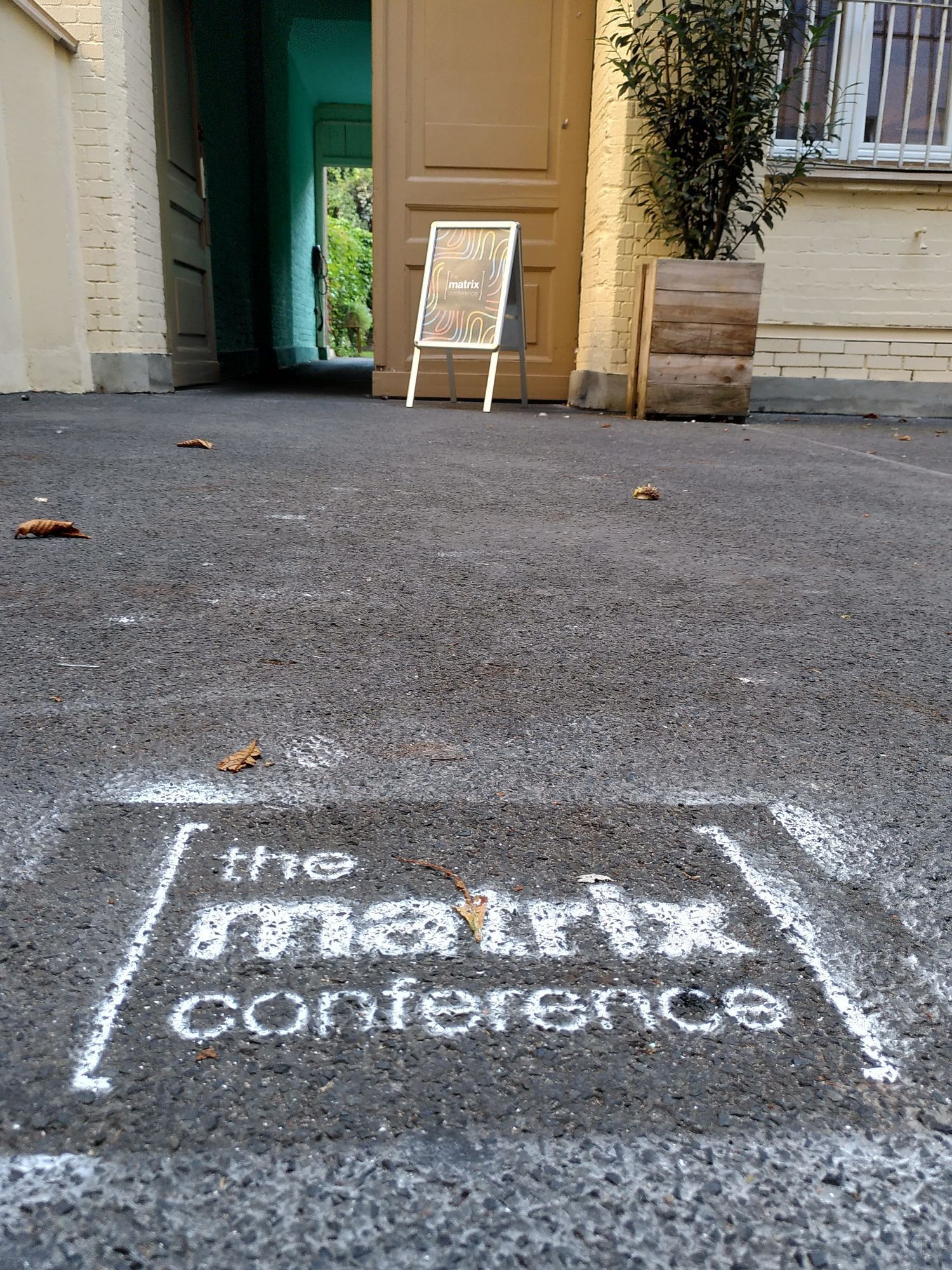 Matrix conference logo sprayed on the floor, open portal to the conference venue in background.