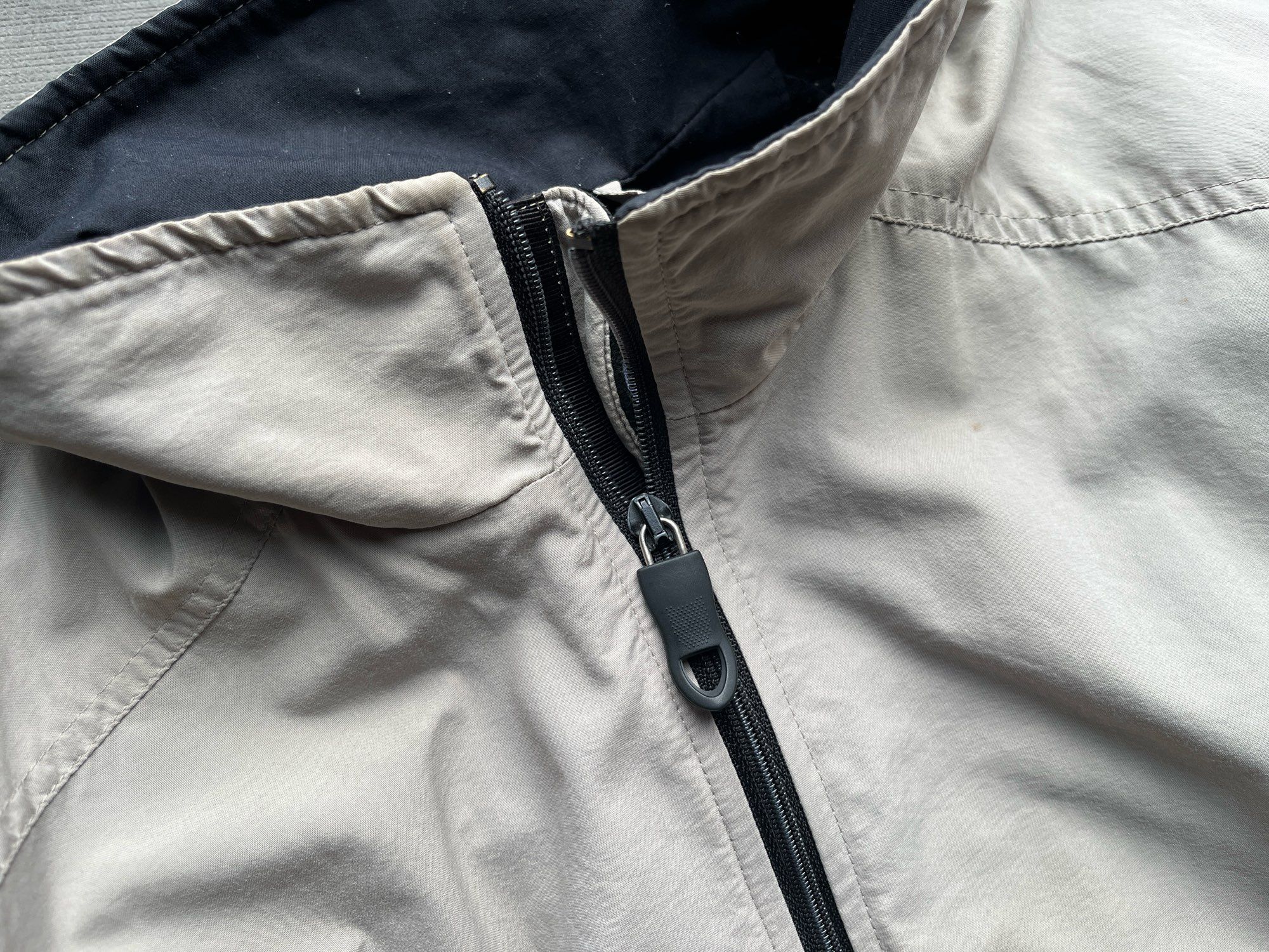 Top of pale cream jacket showing a replacement zip pull.