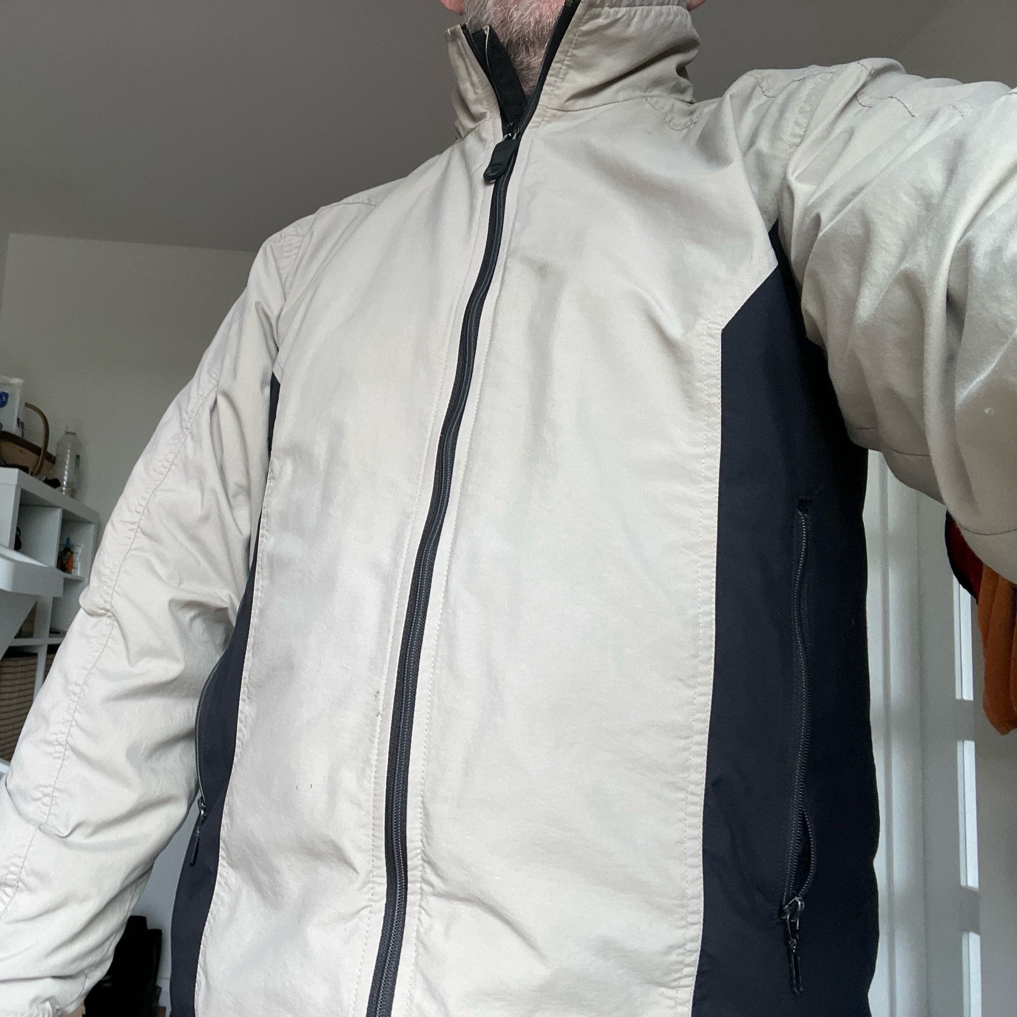 Rogan Goa jacket being modelled   A pale cream coloured jacket with black central zip, and black side panels.