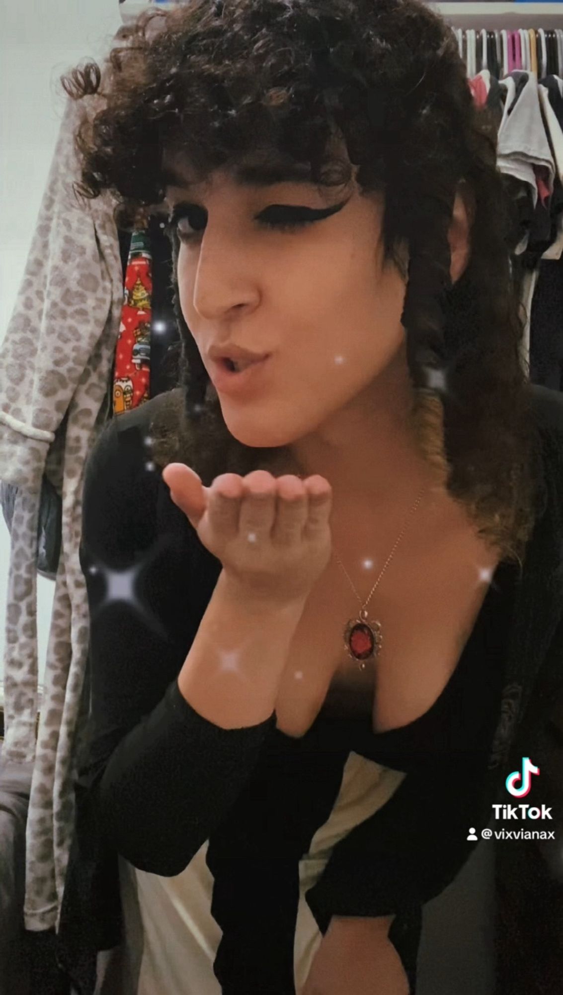 screenshot of a tiktok video of Vi Viana wearing a low cut black and white dress and a red rose pendant, and she’s blowing a kiss at the camera