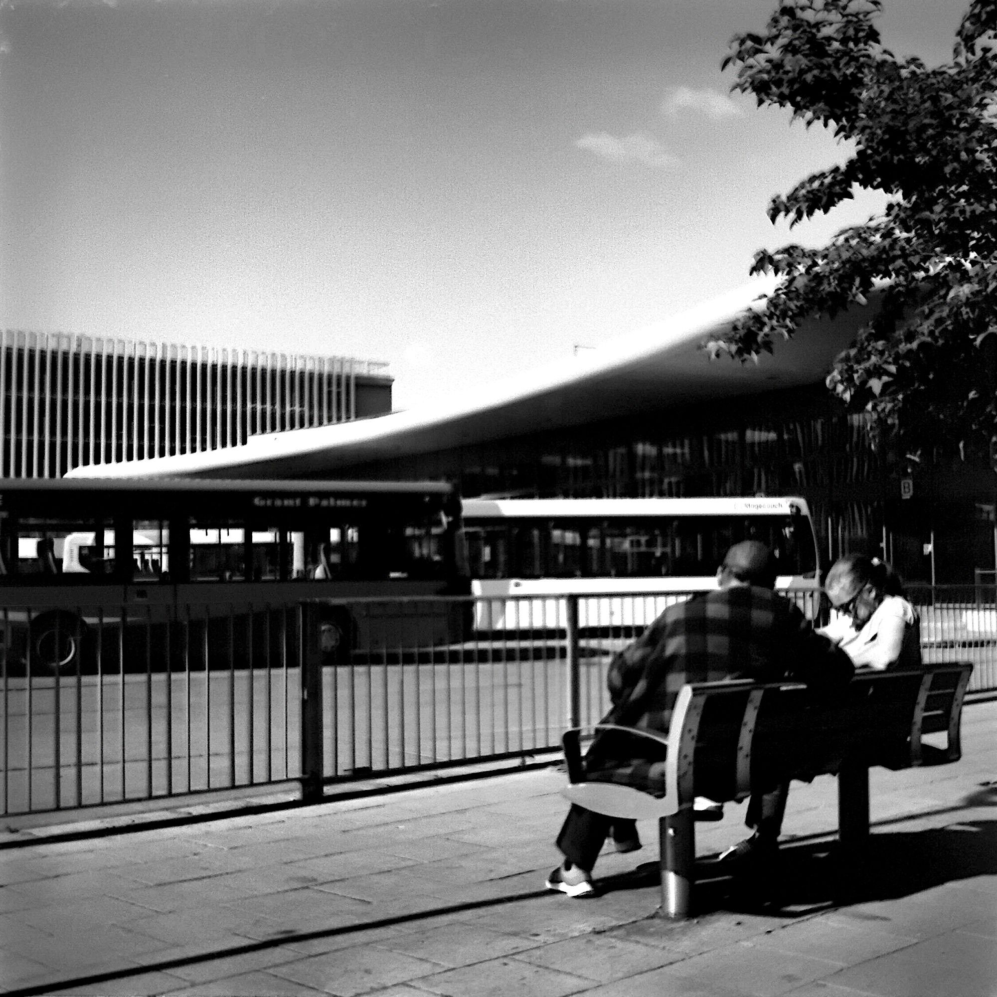 A couple in conversation, sitting on a bench near Bedford Bus Station.