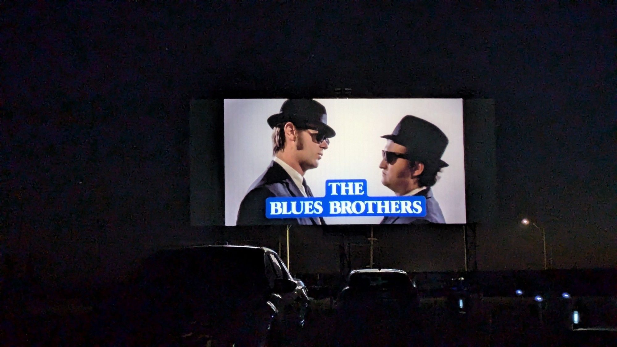 The title card for the movie blues brothers, on the drive in movie screen