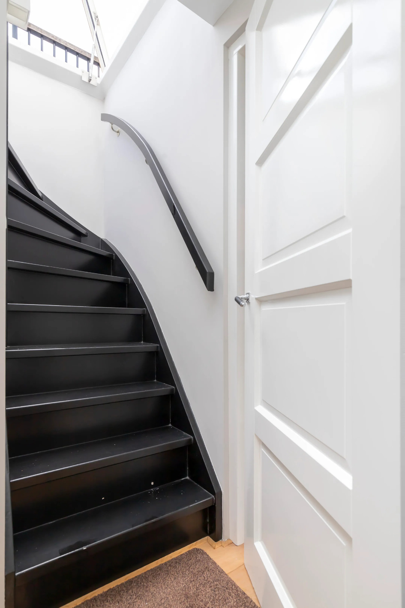 Photo from a current canal house listing showing steps from the front door. The steps are not only incredibly narrow and steep, they curve seven steps up at a near impossible angle, meaning you'd have to press yourself against the wall to make the turn. 