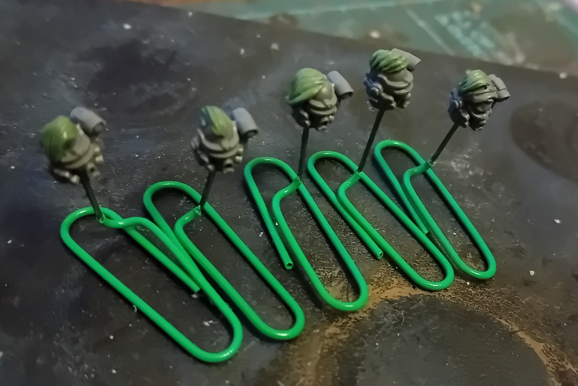 Five plastic Marine heads on paperclip stands. They all have side cuts. They're queerer now.