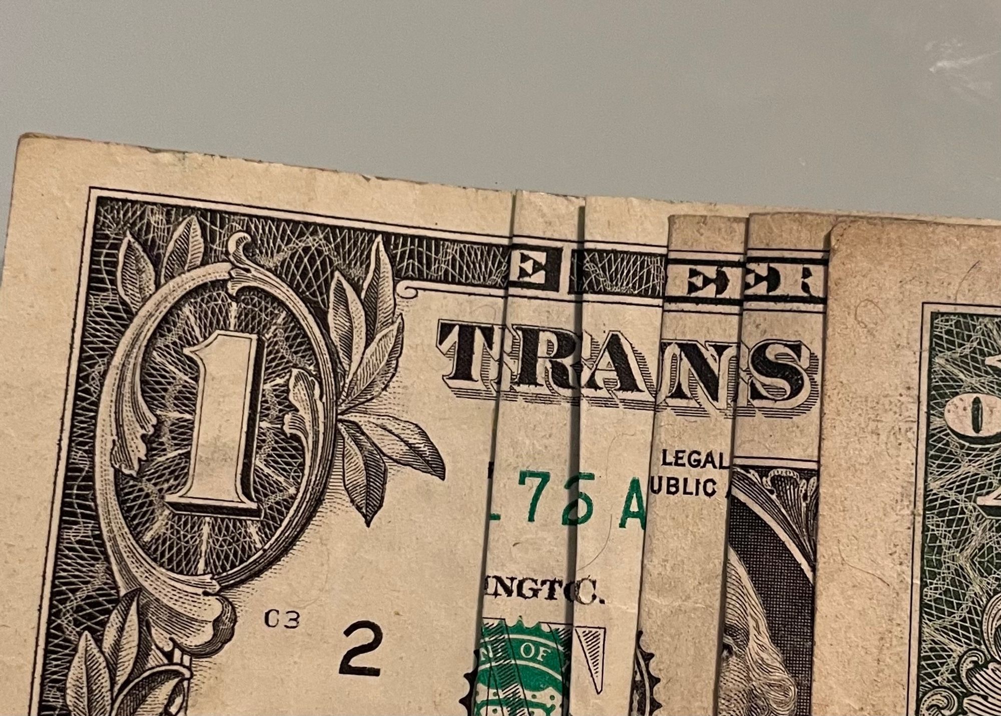 Dollar bill folded to display the word TRANS. 