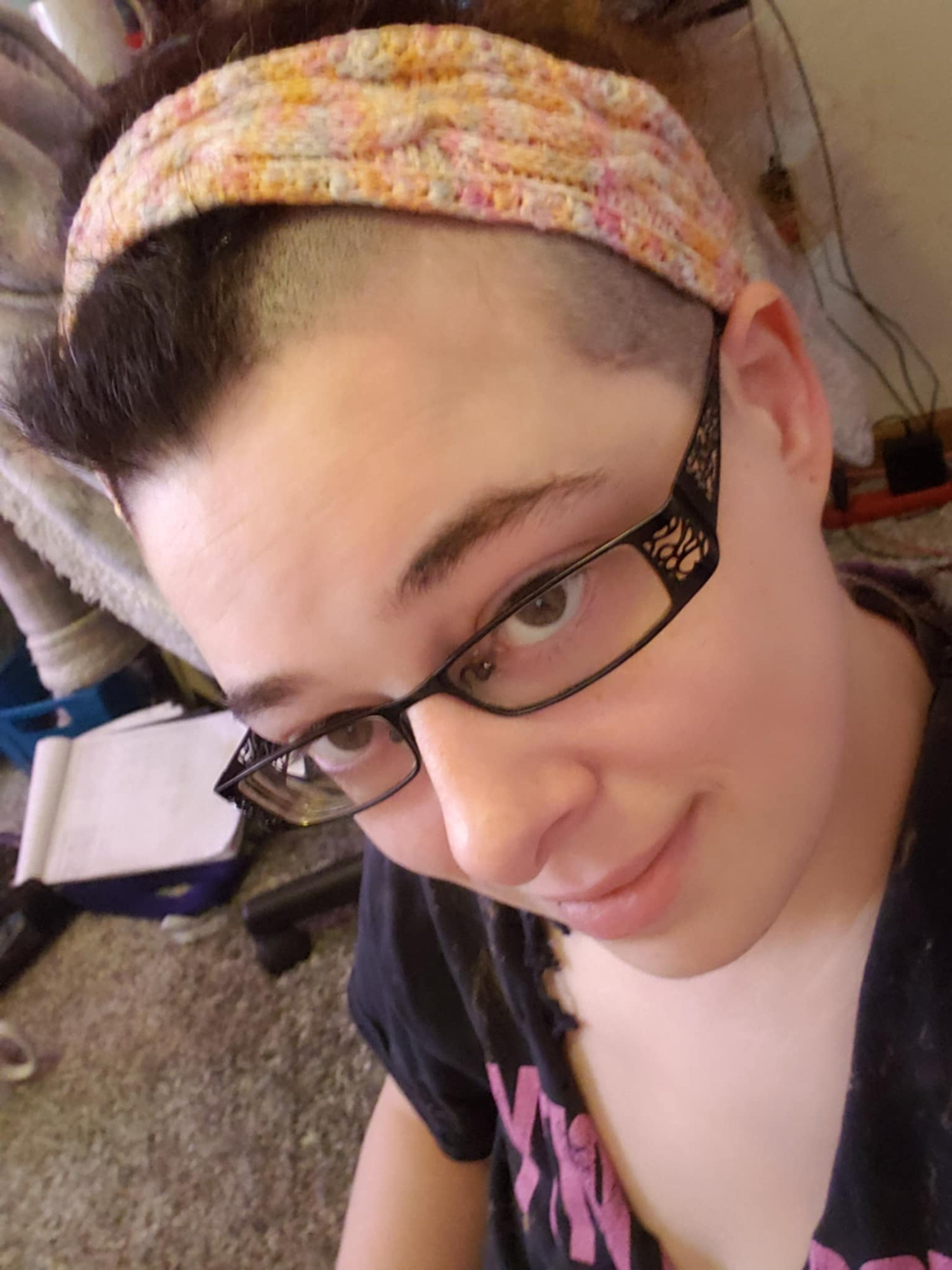 Selfie of me modeling a cable knit headband in the lesbian pride flag colors