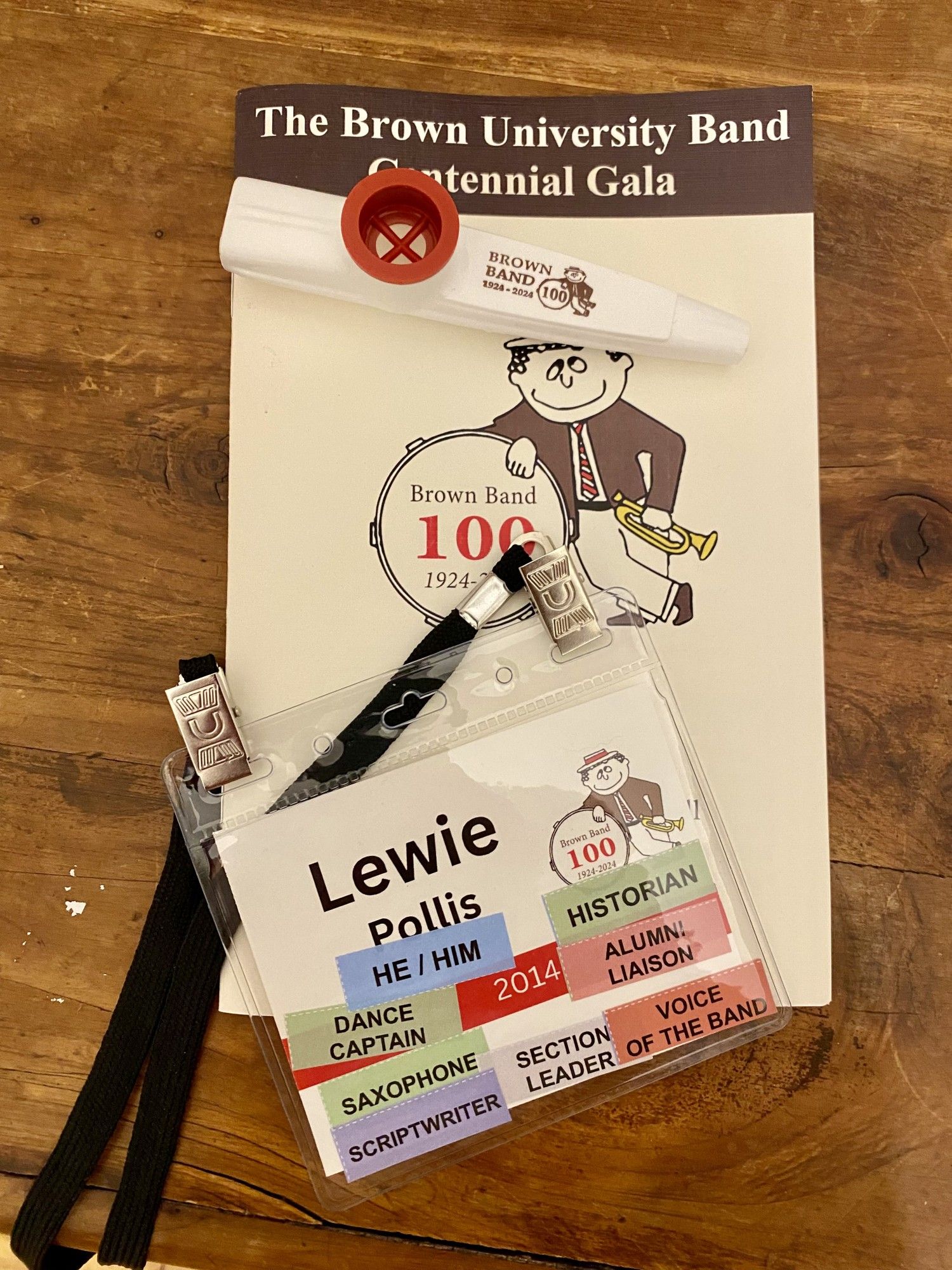 A program, sticker-filled lanyard, and commemorative kazoo from the Brown University Band's centennial gala