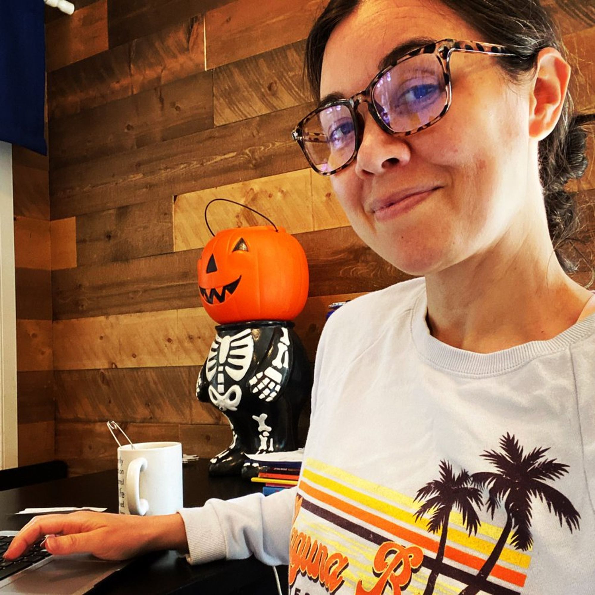 Tara Platt wearing glasses in her and Yuri Lowenthal's home with a pumpkinheaded skeleton nearby.