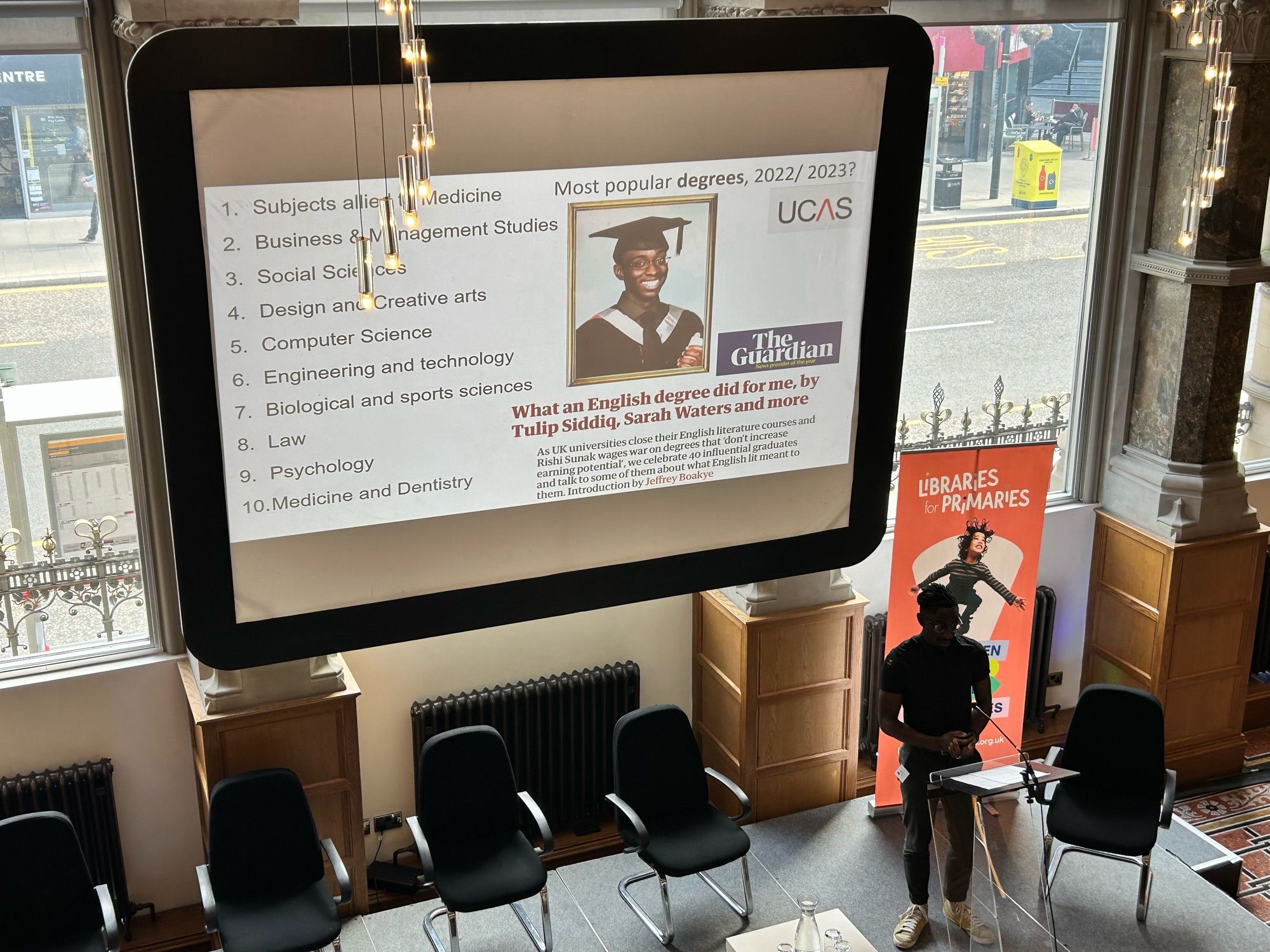 Picture of author, broadcaster, speaker Jeffrey Boakye delivering a keynote. Slide shows top 10 degrees studied in 2022-2023 which does not seem code English. Slide also shows a screen grab of a Guardian article focused on the benefits of studying degree in  English.