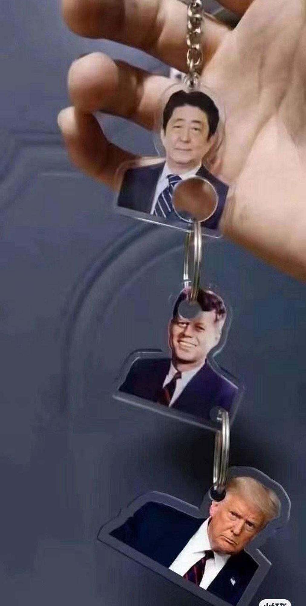 A triple keychain with Shinzo Abe, John F. Kennedy, and Donald Trump. 

Abe has a hole in his chest, where he got shot. Below is Kennedy with a hole in his head and a hole in his shoulder, where he got shot. Last is Trump with a hole in his ear, where a piece of glass cut him after he was shot at.