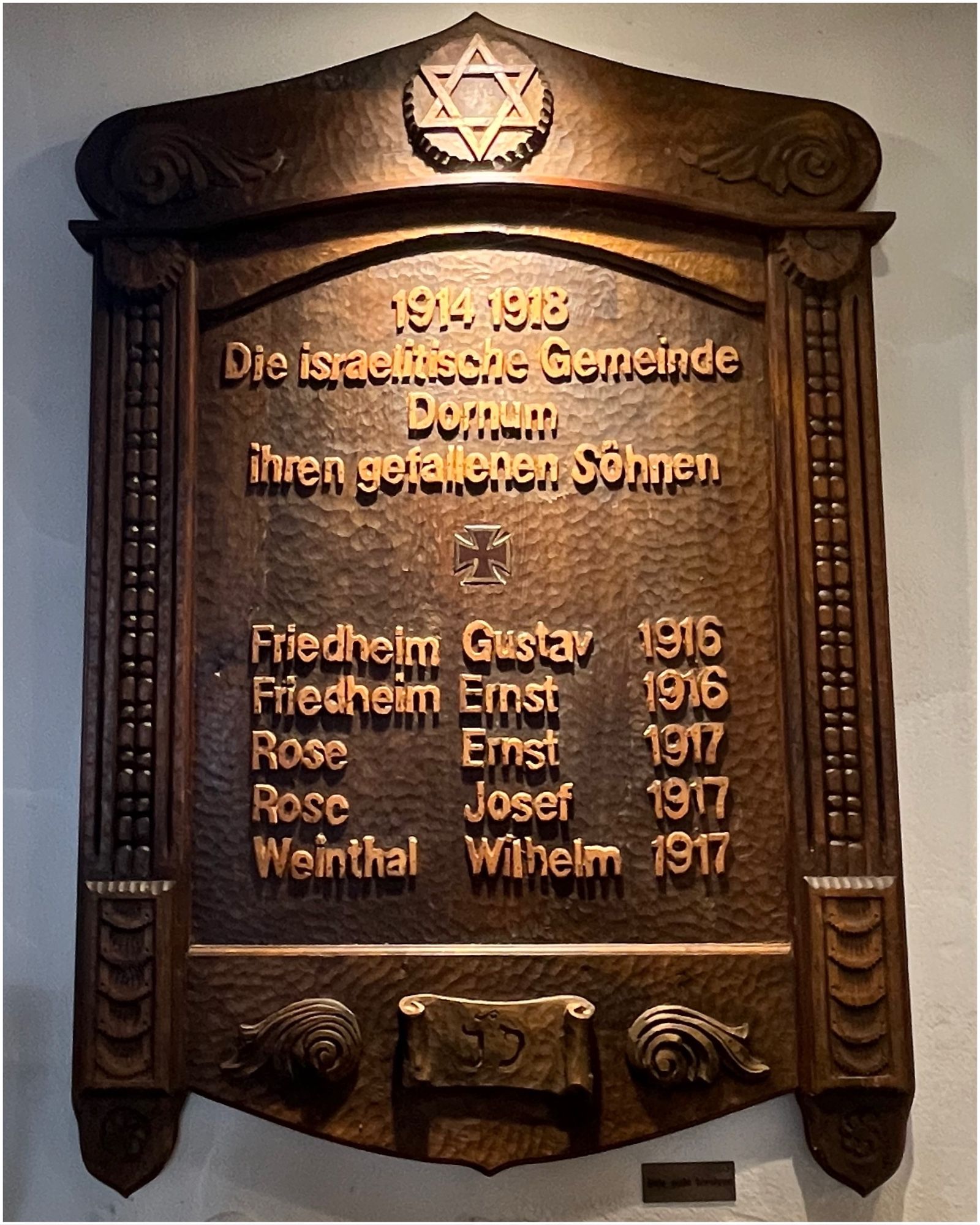 Holztafel mit Schnitzereien. Oben ein Davidstern. In der Mitte die Inschrift: „1914-1918. Die israelitische Gemeinde Dornum ihren gefallenen Söhnen.“ Dazu eine Liste mit fünf Namen.