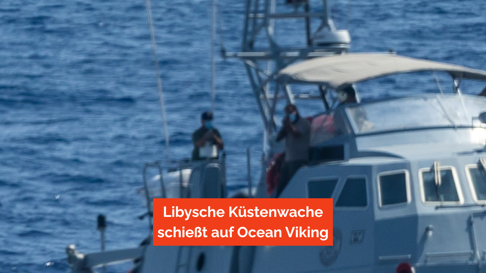 Zwei bewaffnete Männer auf einem Schiff der Libyschen Küstenwache richten ihre Waffen auf die Ocean Viking.