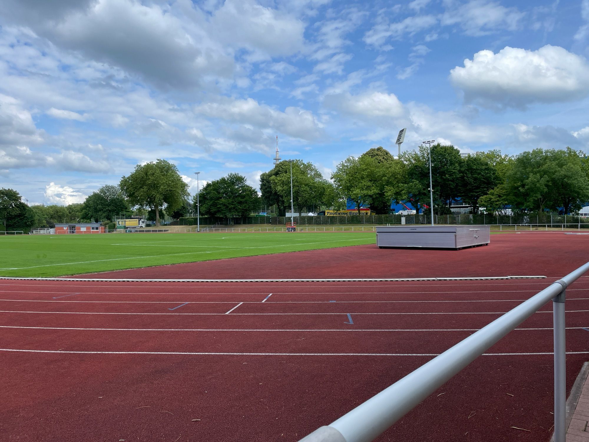 Der Leichtathletikplatz vom VfL Bochum, umrandet von Bäumen. Im Hintergrund sitzt man die Flutlichter vom Ruhrstadion.