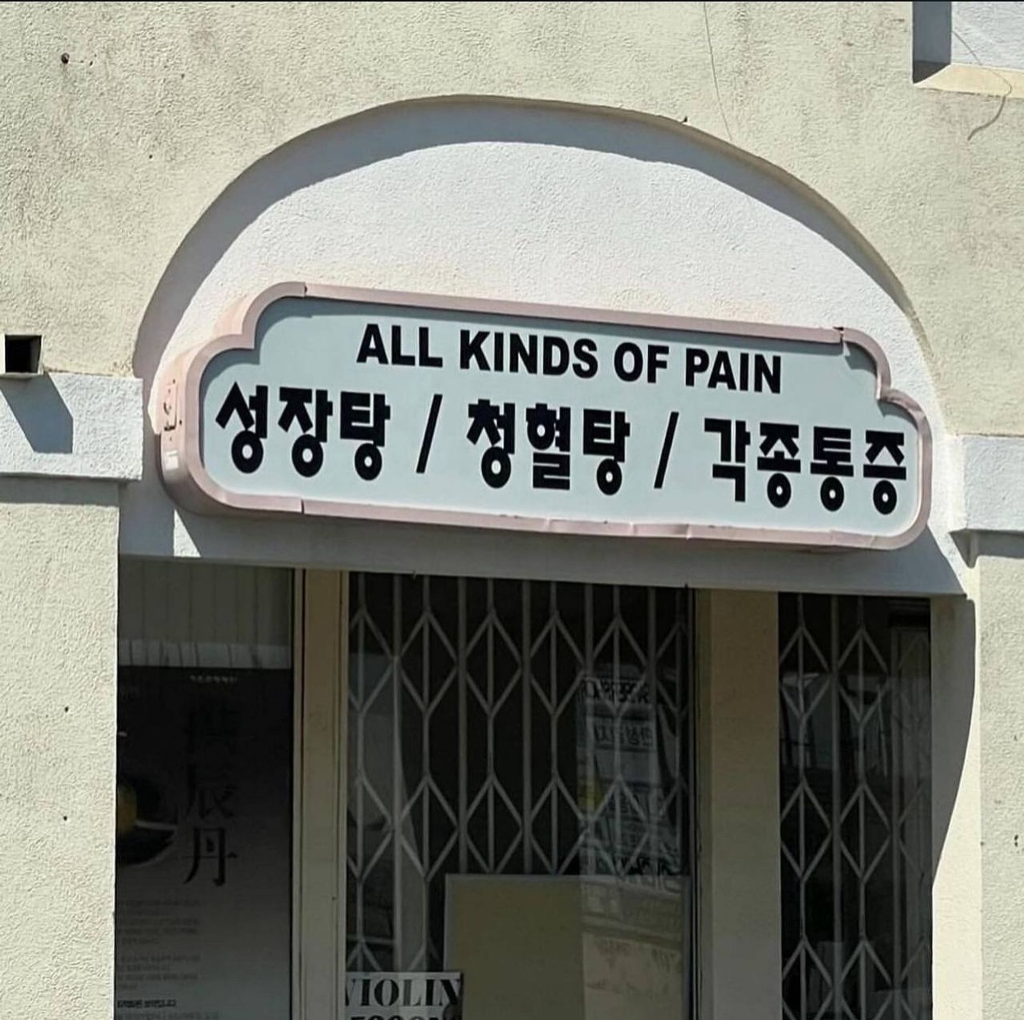 a shop sign in Korean which the meme maker has translated as 

ALL KINDS OF PAIN