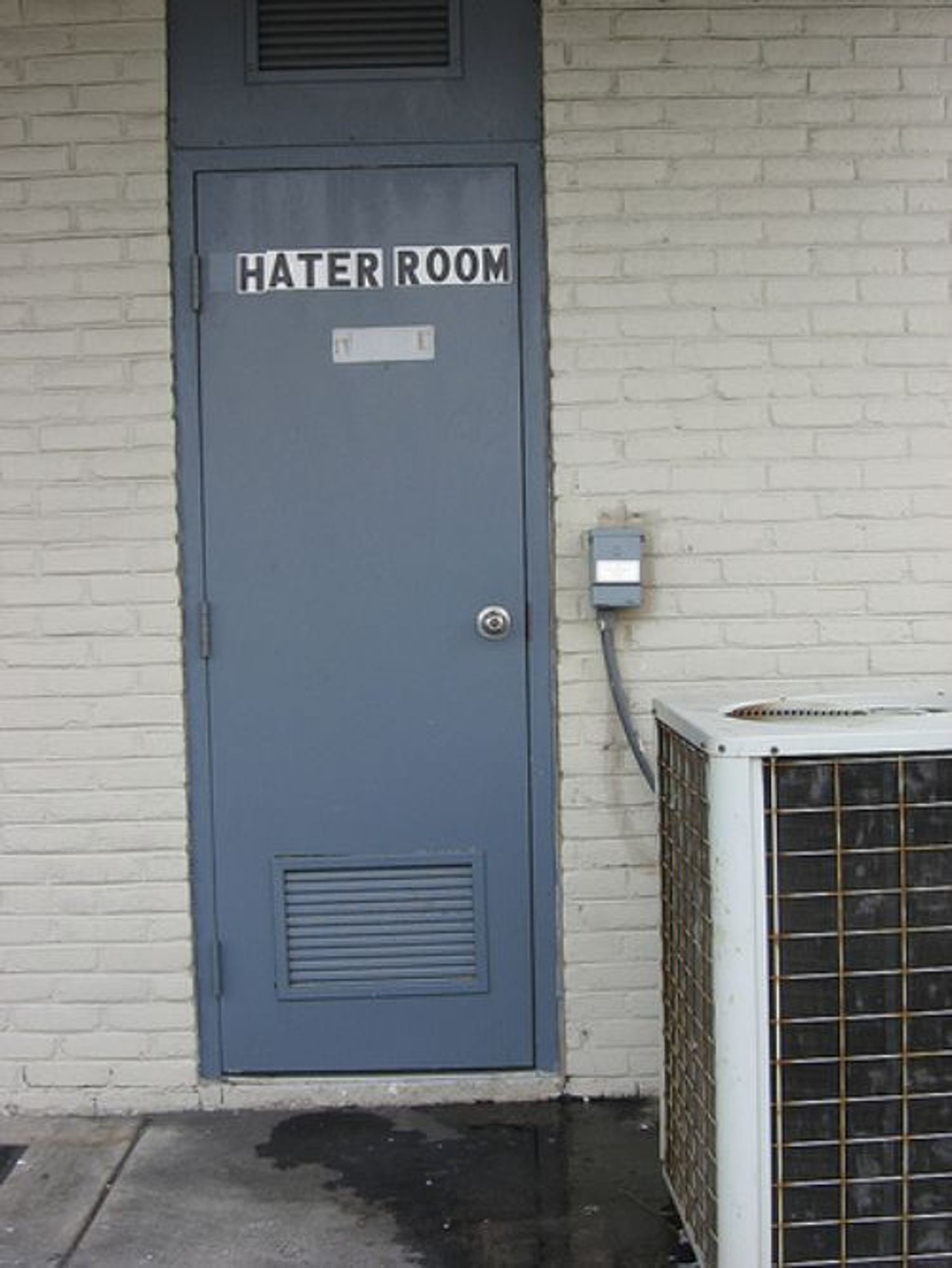 brick wall with a gray door labled

HATER ROOM