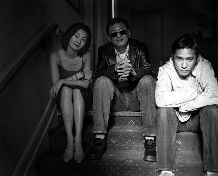 Maggie Cheung, Wong Kar-wai & Tony Leung sitting on carpeted stairs