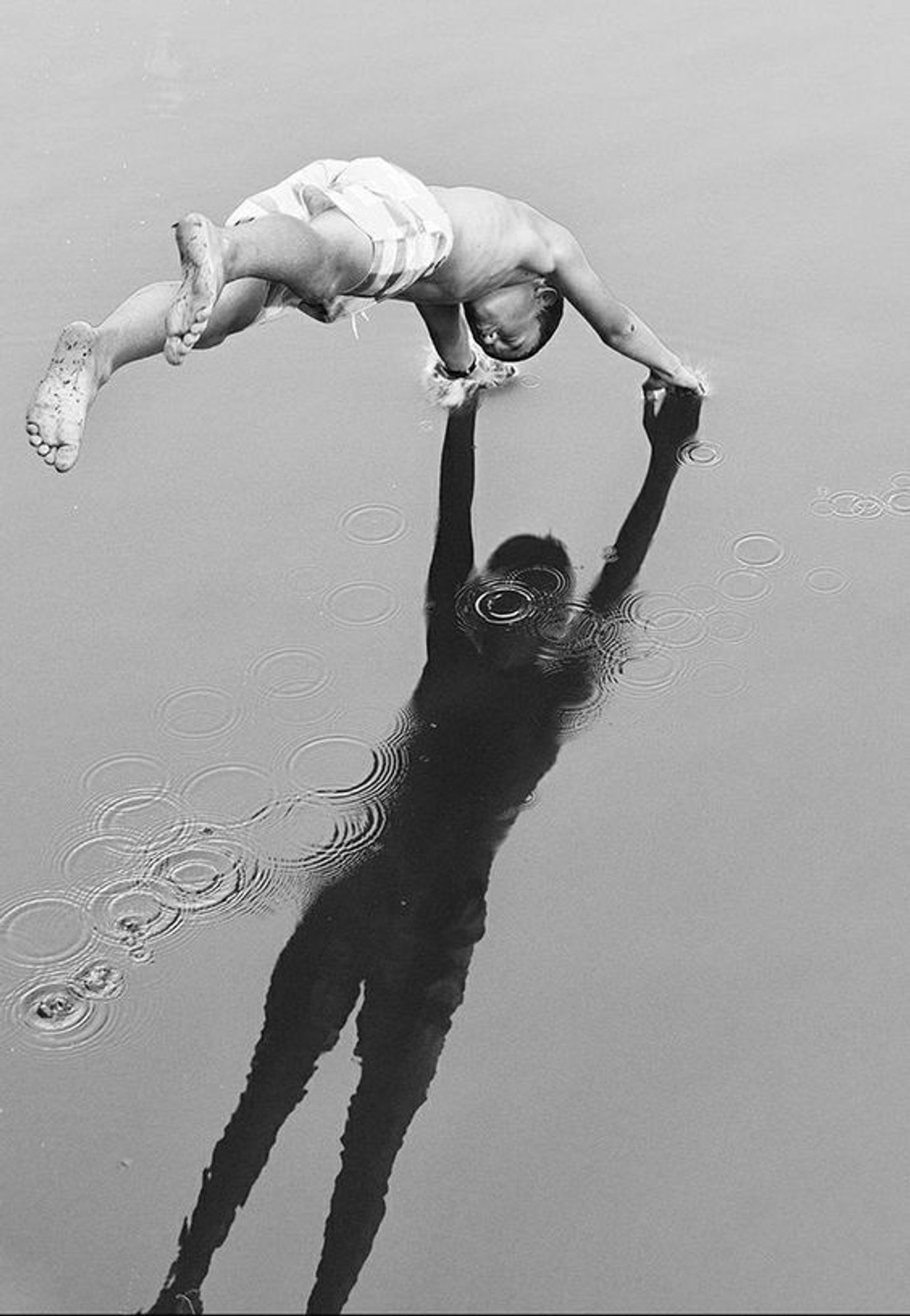 photo of a man diving into his own shadow a body of water