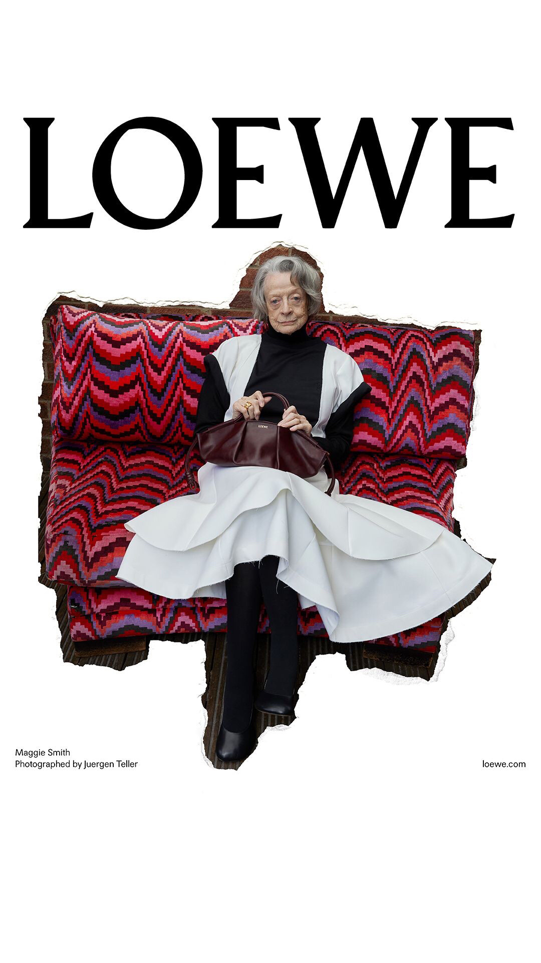 Maggie Smith in a Loewe ad. Black & white pinafore seated on a couch with a zigzag pattern.