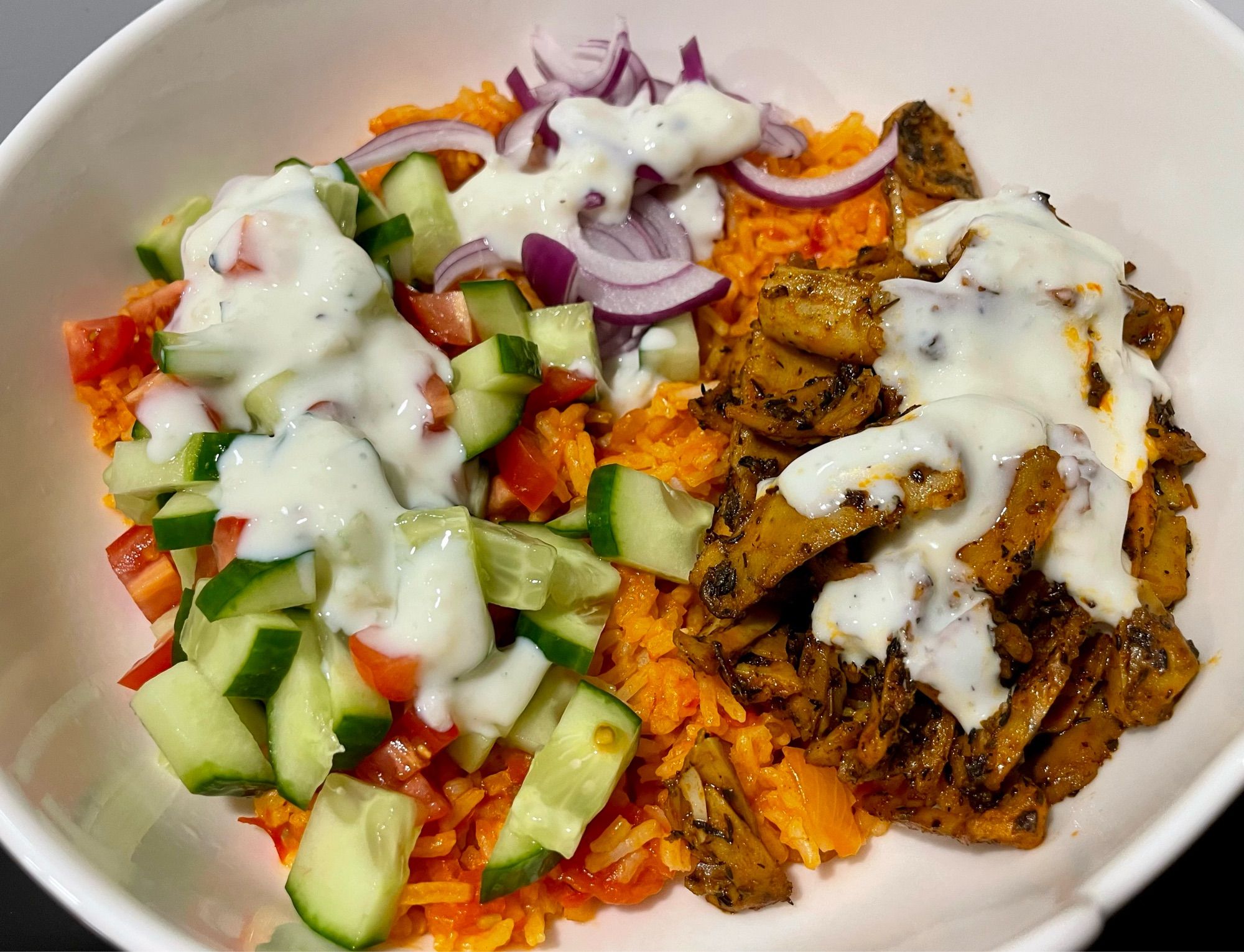 djuvec rice, Kebab "meat", red onions, tomato, cuccumber topped with garlic sauce. All vegan.