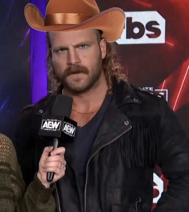 Hangman Adam Page with an impressive mustache and a black fringed leather jacket with a brown cowboy hat poorly photoshopped onto his head. 