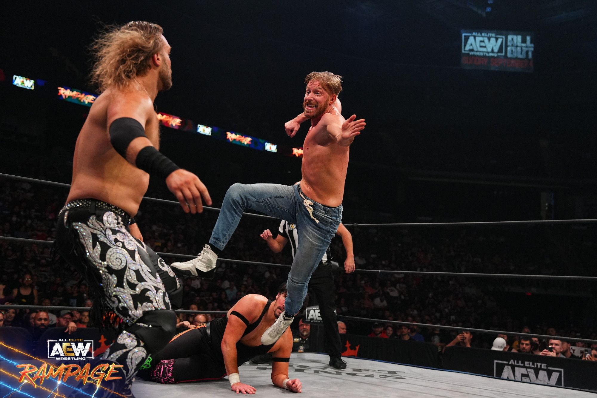 Orange Cassidy about to orange punch Hangman during a match on AEW Rampage, Chuck Taylor is laying like a damsel in distress in the background.