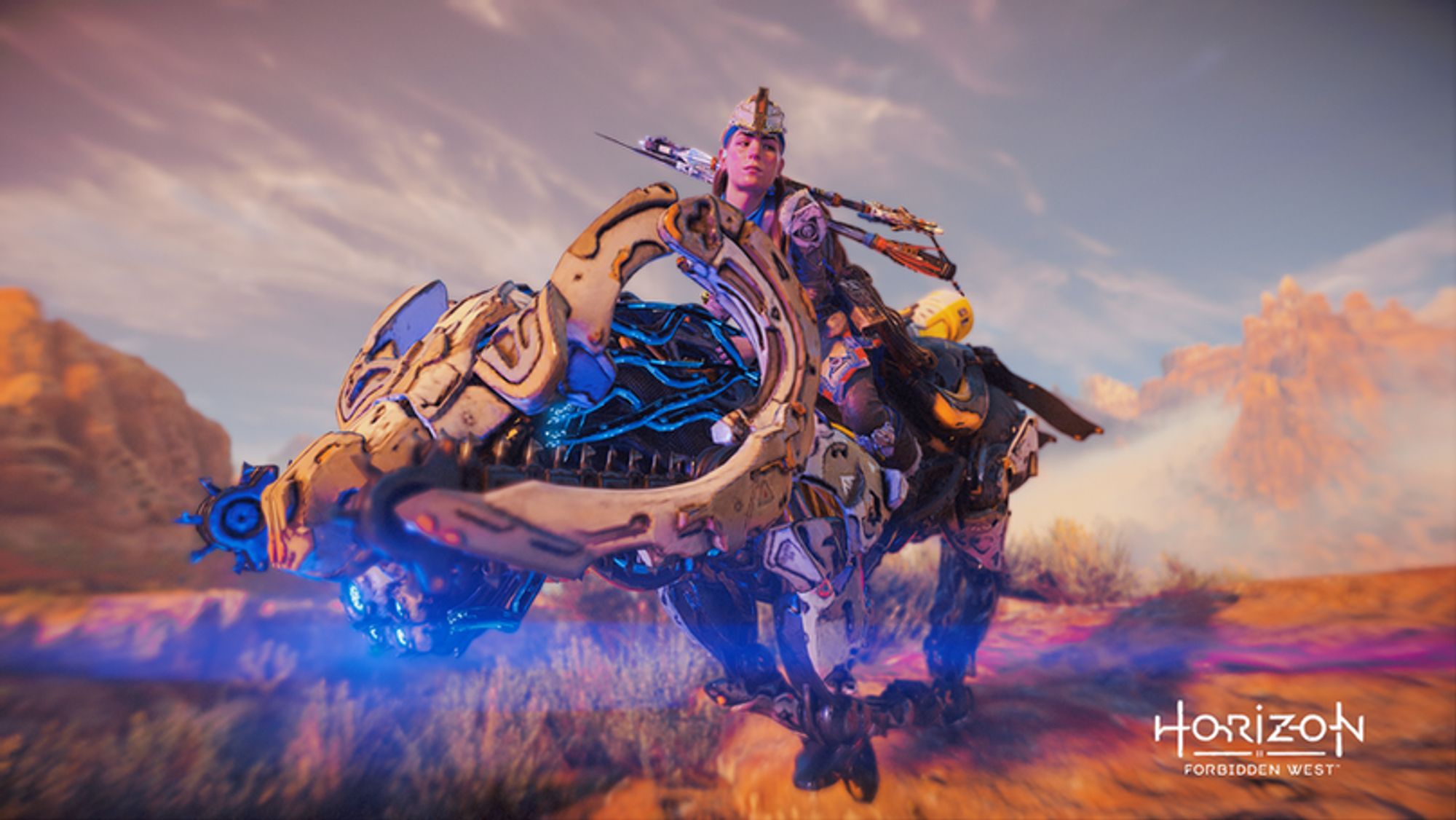 Aloy on a mount, speeding through the landscape as she turns to look behind her.