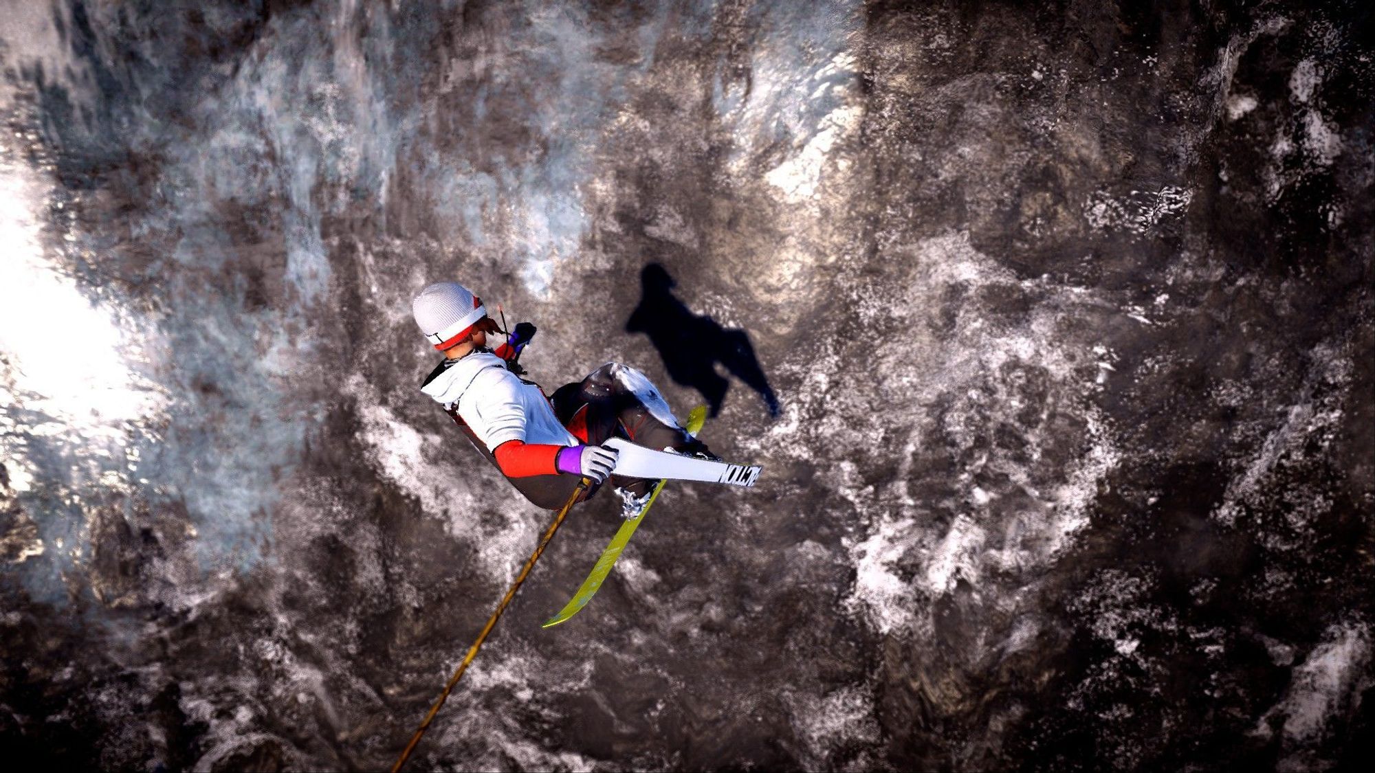 A skier in flight, holding a tail grab and looking back at her shadow casted on the stone she is flying past.