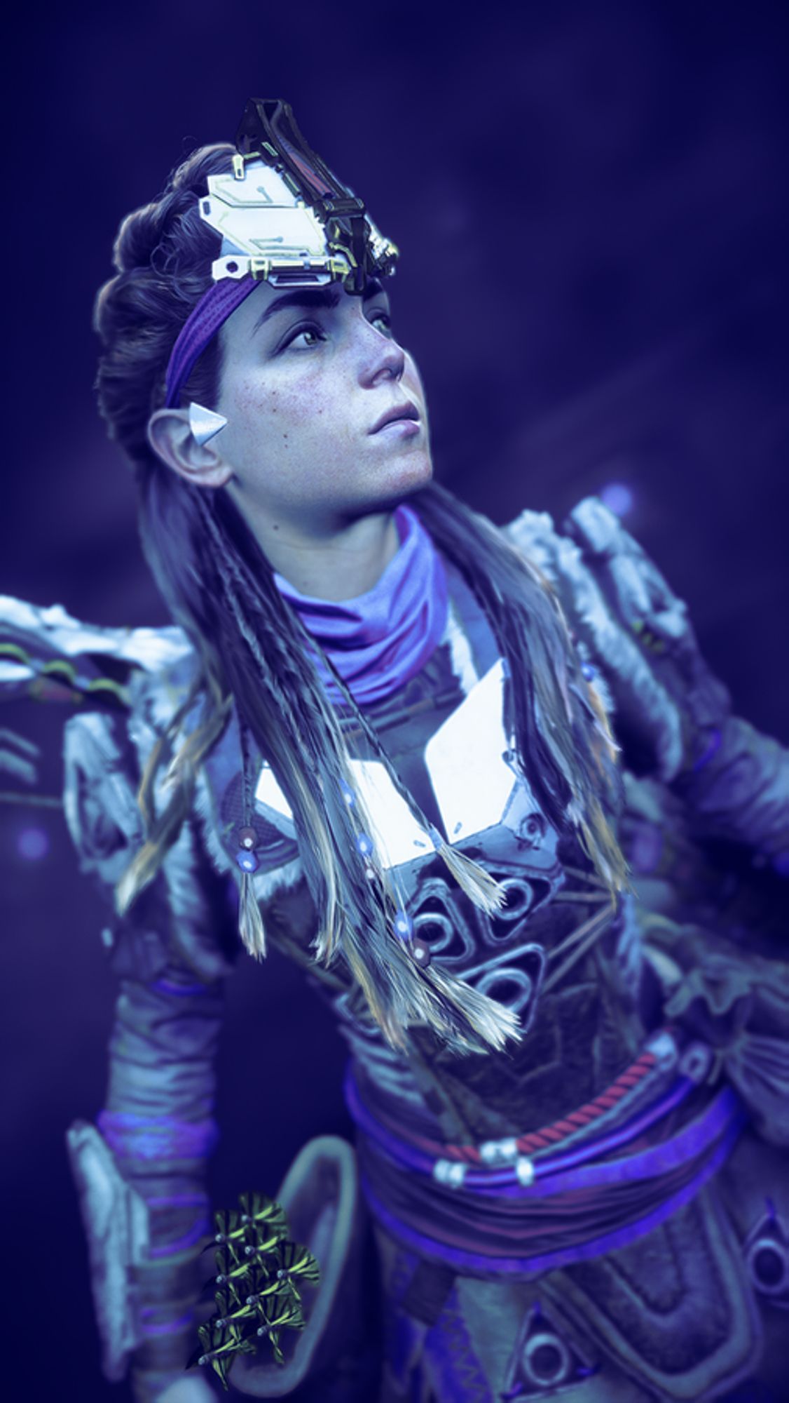 Aloy, looking to the right of the viewer, under a blue light.