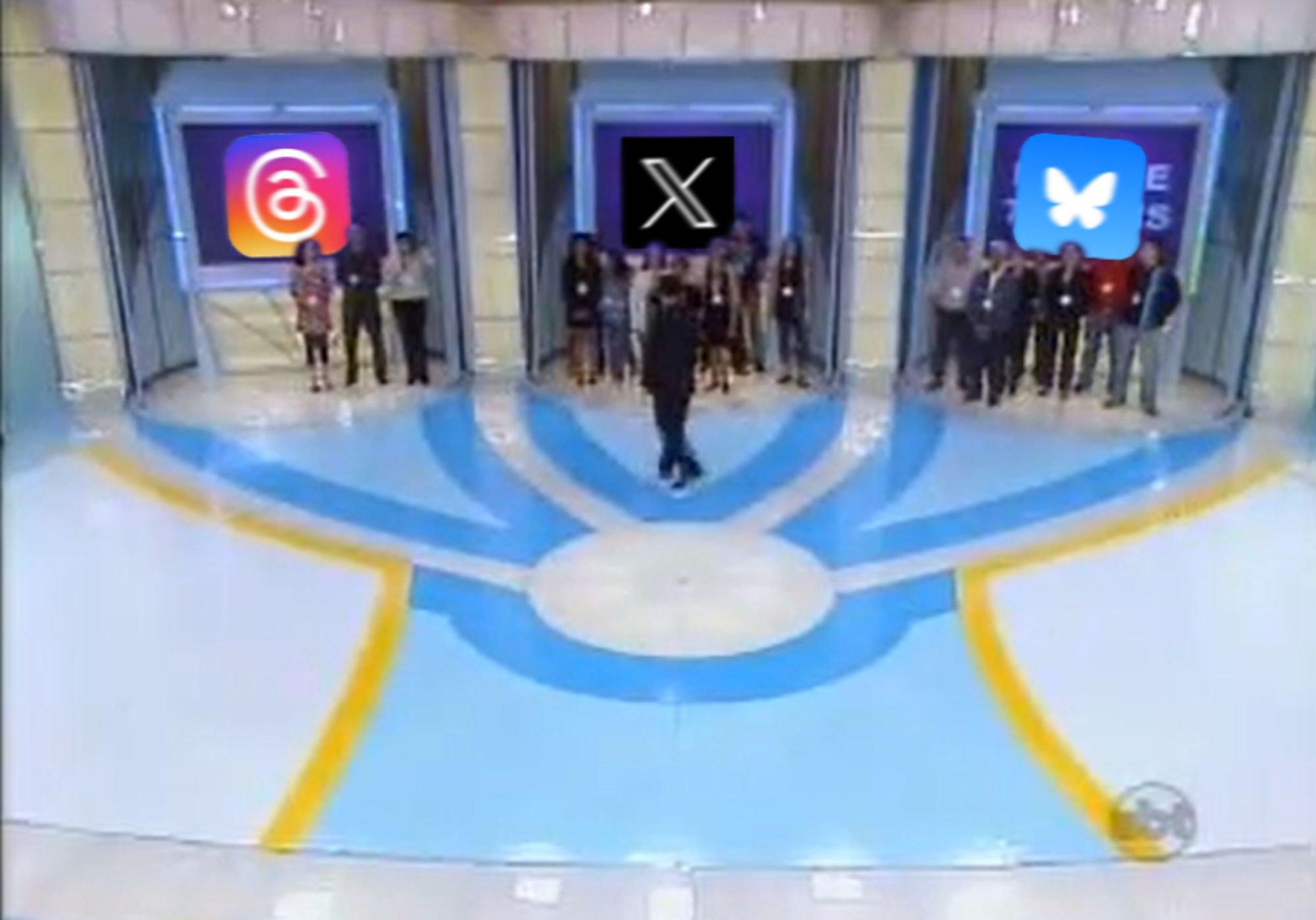 Cenário do programa Tentação do SBT, onde o palco branco com azul tem o chão pintado com três linhas que vão para três estruturas no fundo que lembram elevadores. Cada uma delas mostra num telão as logos das redes sociais Threads do Instagram, X que é o antigo Twitter e Bluesky. São vistas pessoas em cada uma, sugerindo que elas escolheram uma das redes. X e Bluesky tem entre seis pessoas e nove pessoas, Threads tem apenas três.