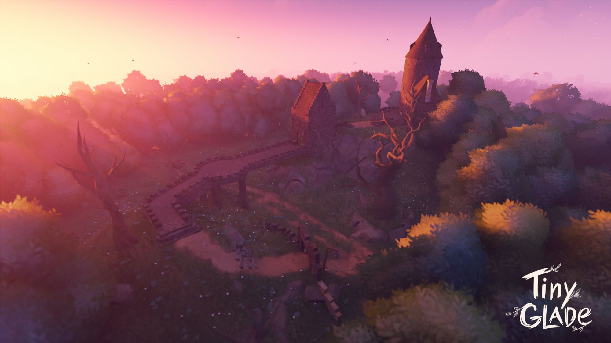 Tiny Glade screenshot showing a grassy, ruined bit of stonework with a full walkway that curls to a gatehouse and then to a mysterious tower on a hill. There's a huge gnarled tree below the hill, and several dotting the landscape. It is a burst of red-orange sunset light and shows off the full glade with the paths, twisting stonework and the mysterious tower.