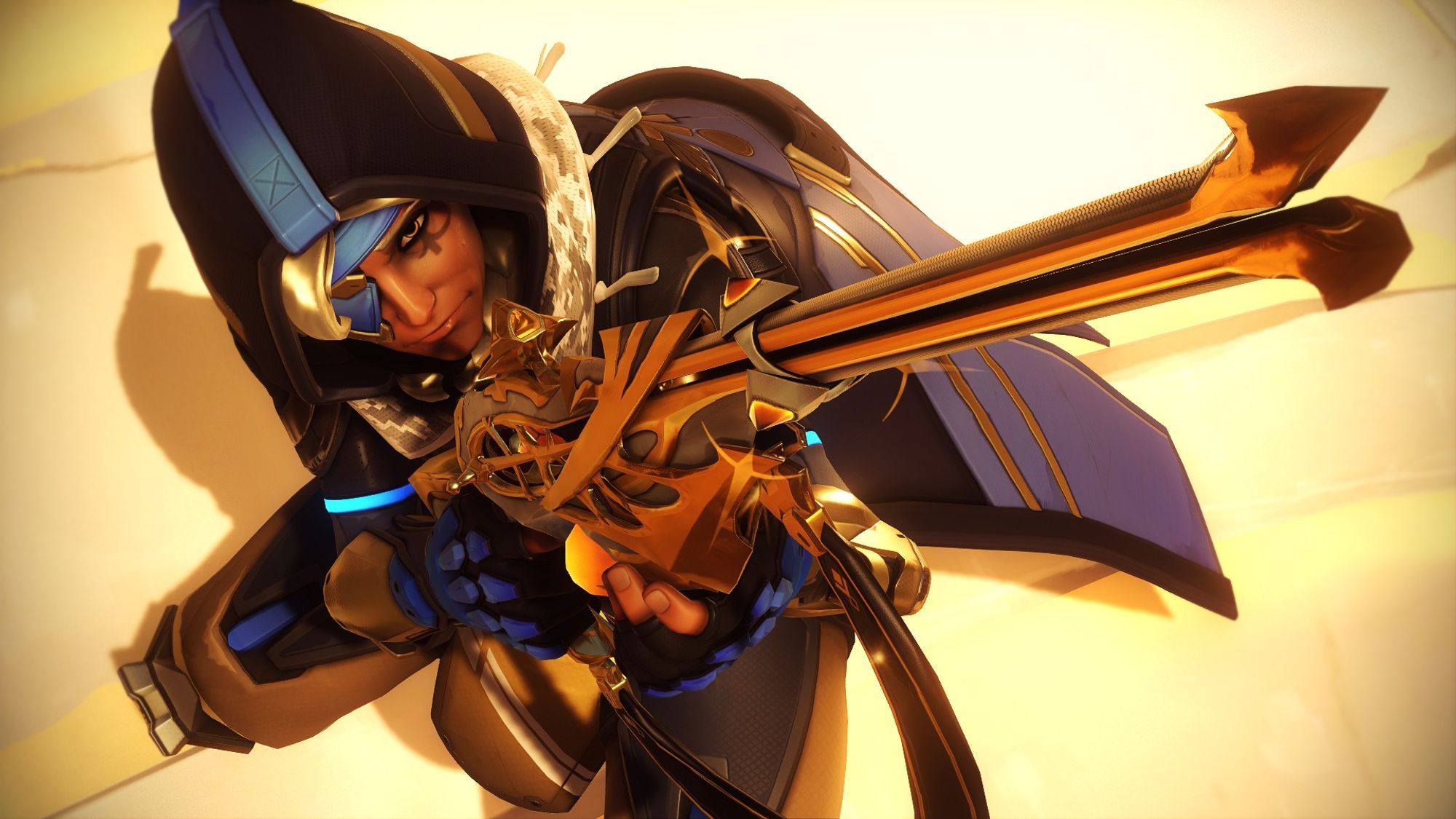 Overwatch 2 screenshot of Ana in her basic Overwatch 2 outfit. It is a tactical suit with a long blue duster with hood, a scarf that looks similar to a keffiyeh, an eye patch and a hijab under her hood. Her suit underneath is beige. She has a very ornate white and gold-detailed sniper rifle with crystal details. The shot is in a very sharp, overhead angle that compresses her pose down to the ground, with the muzzle of the rifle almost out of frame.