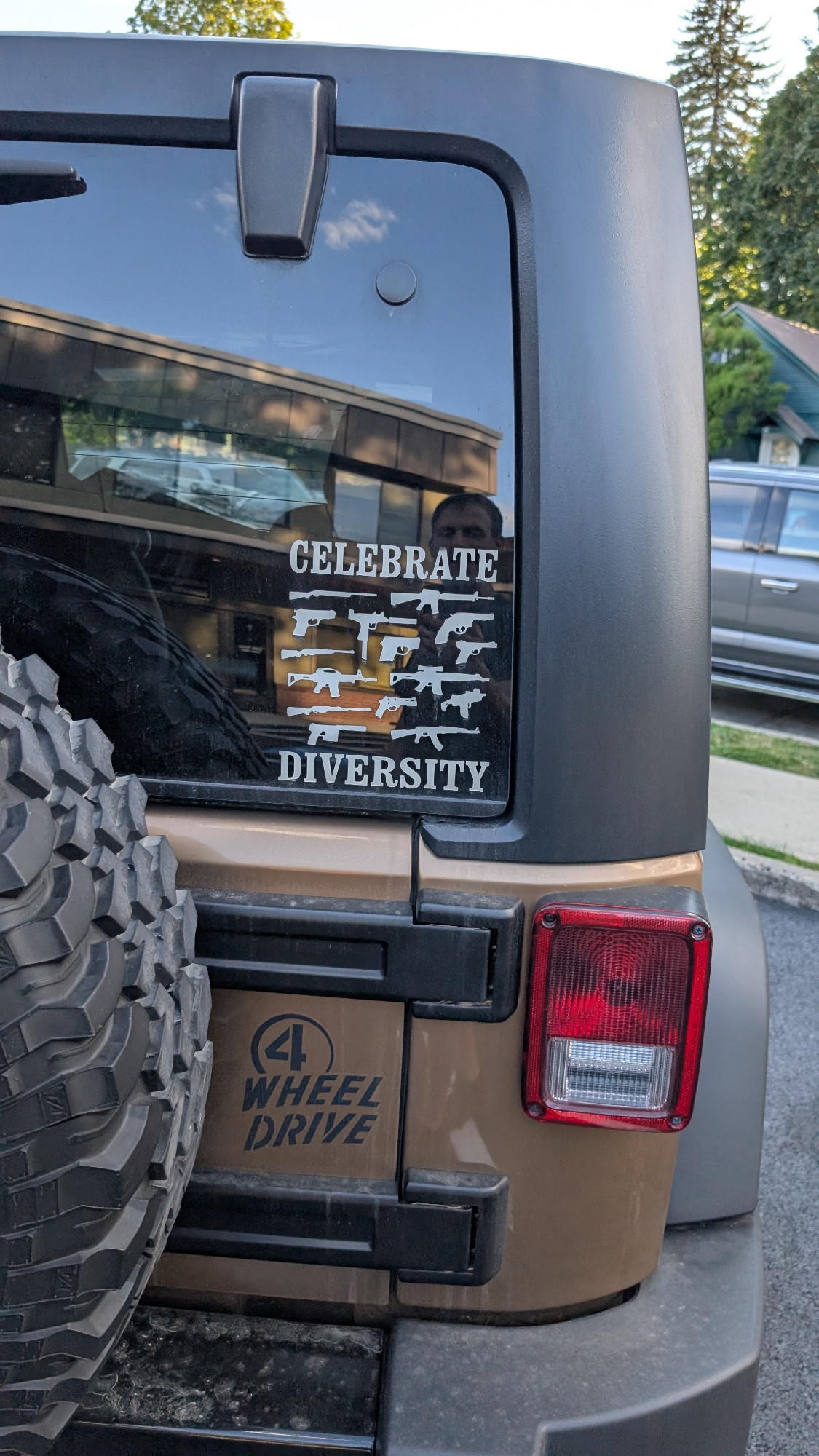 A jeep with a window decal that says "celebrate diversity" except it has pictures of many kinds of guns 🥺