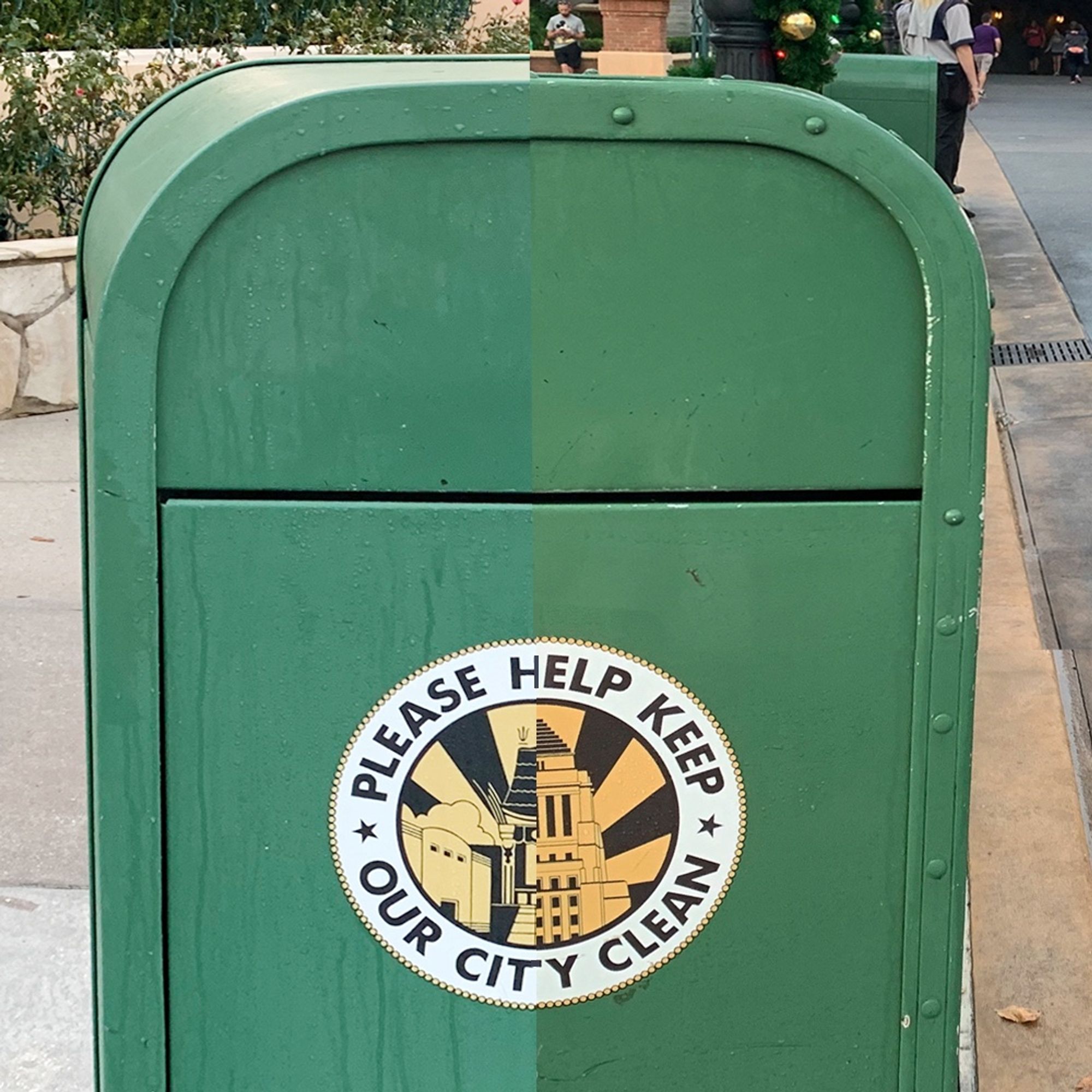 A green trash can split down the middle with a circular label that reads "Please Help Keep Our City Clean" and features an illustration of city buildings on each side