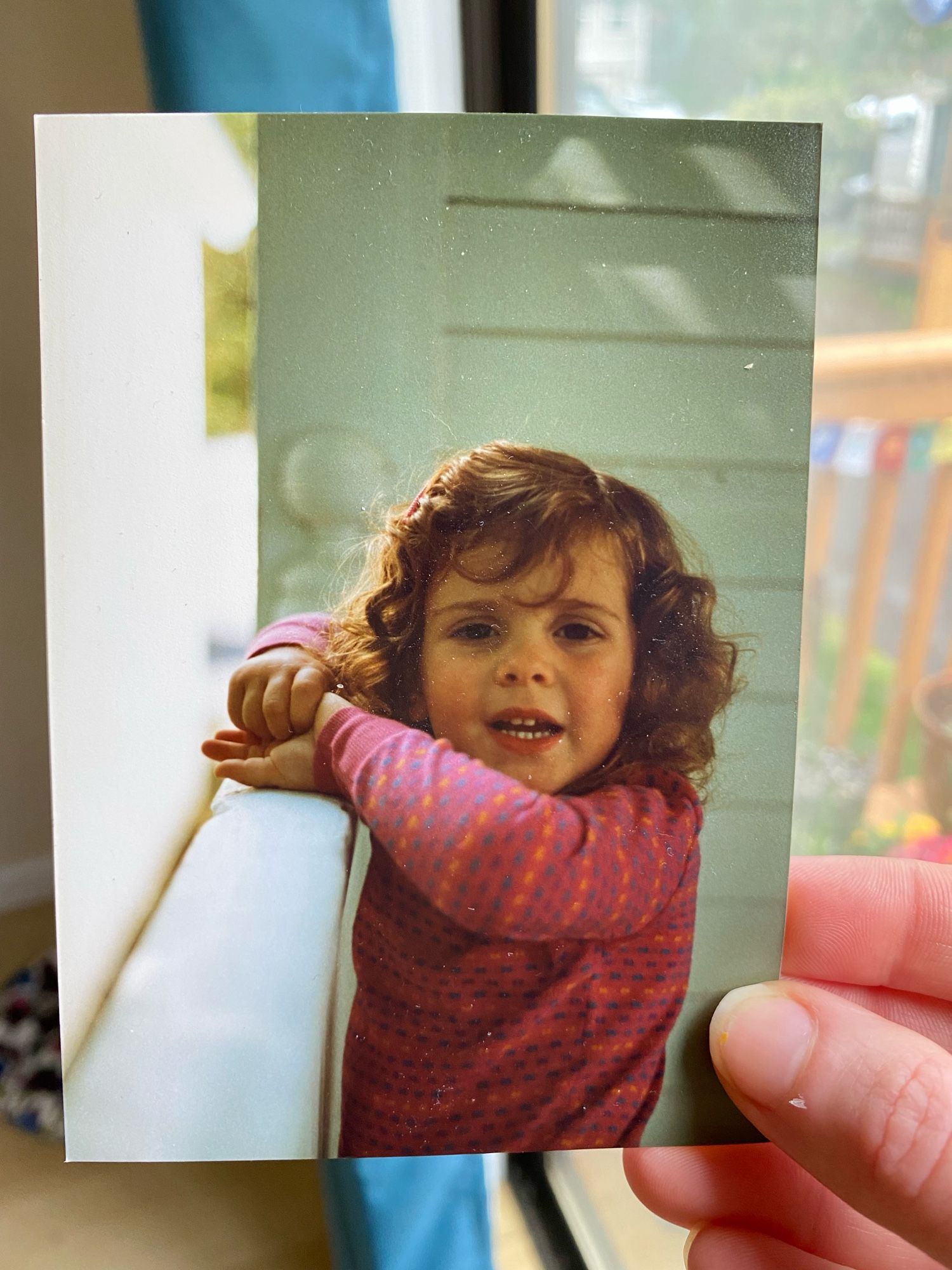 Photo of a photo of me when I was about 3 or 4, so peak weirdo years. Naturally I’m wearing a patterned top featuring pink, orange and purple