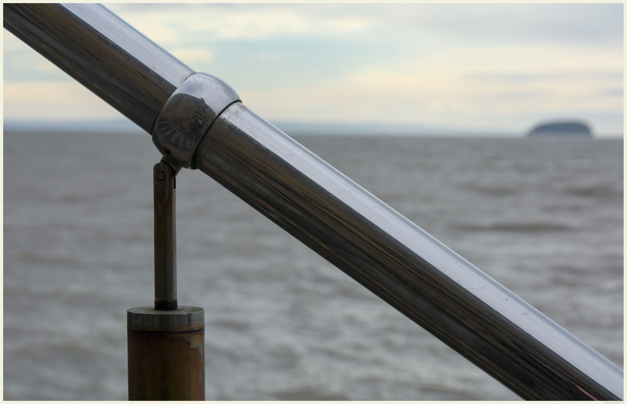 A stainless steel handrail and one of it's uprights - which, patently, isn't stainless steel, as it is subject to rust.

The hand runner drops from top left corner to bottom right corner, at an angle of about 45 degrees.

From the bottom of the photo to the bottom of the sky is the, de-focused, Bristol Channel.

At the right where the sea meets the cloudy sky is, again de-focused, Steepholm Island.

This Image is also a bit of a selfie too!