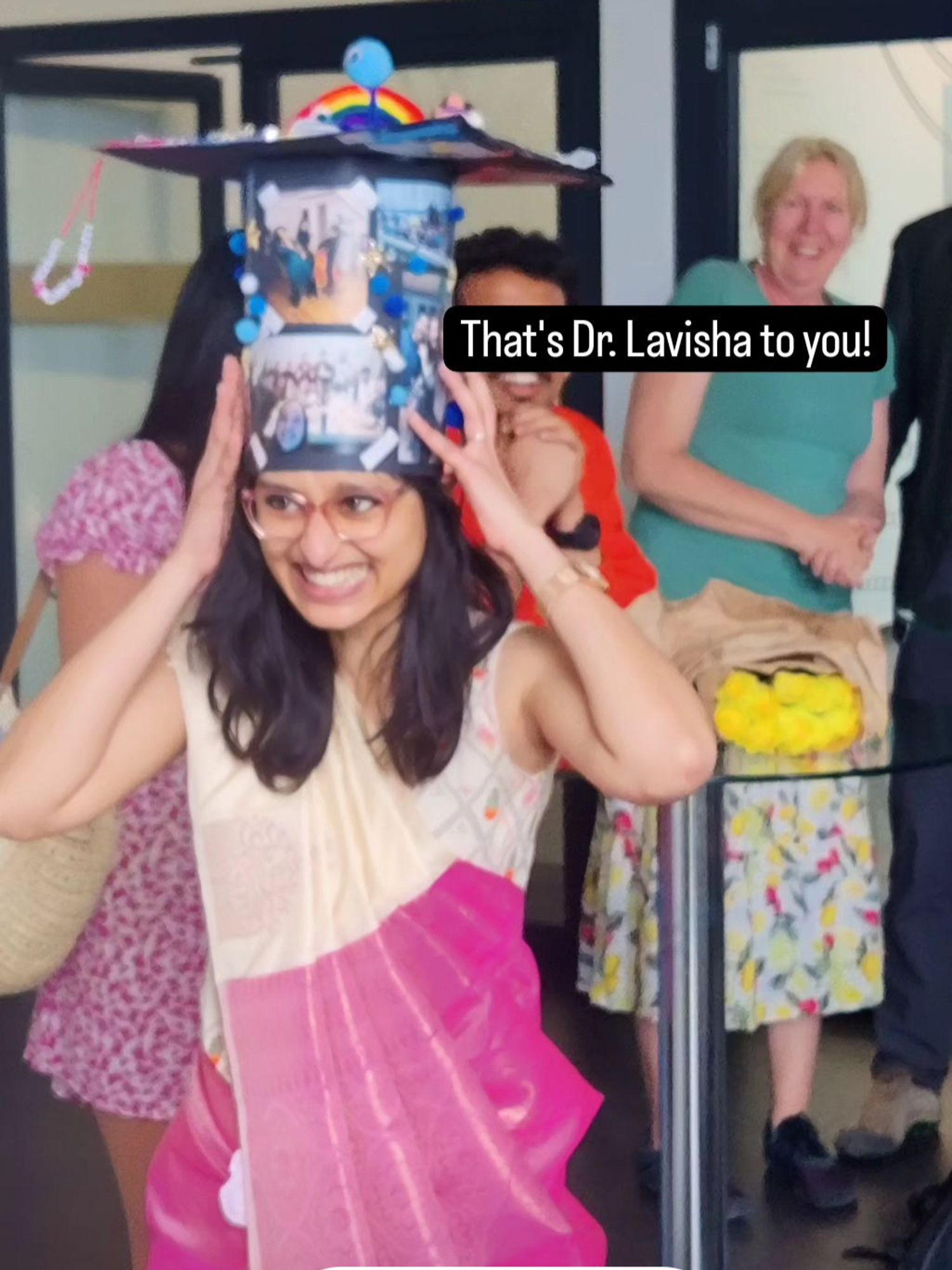 A photo of Lavisha in a saree wearing her PhD graduation hat, with a super huge full toothed smile on her face