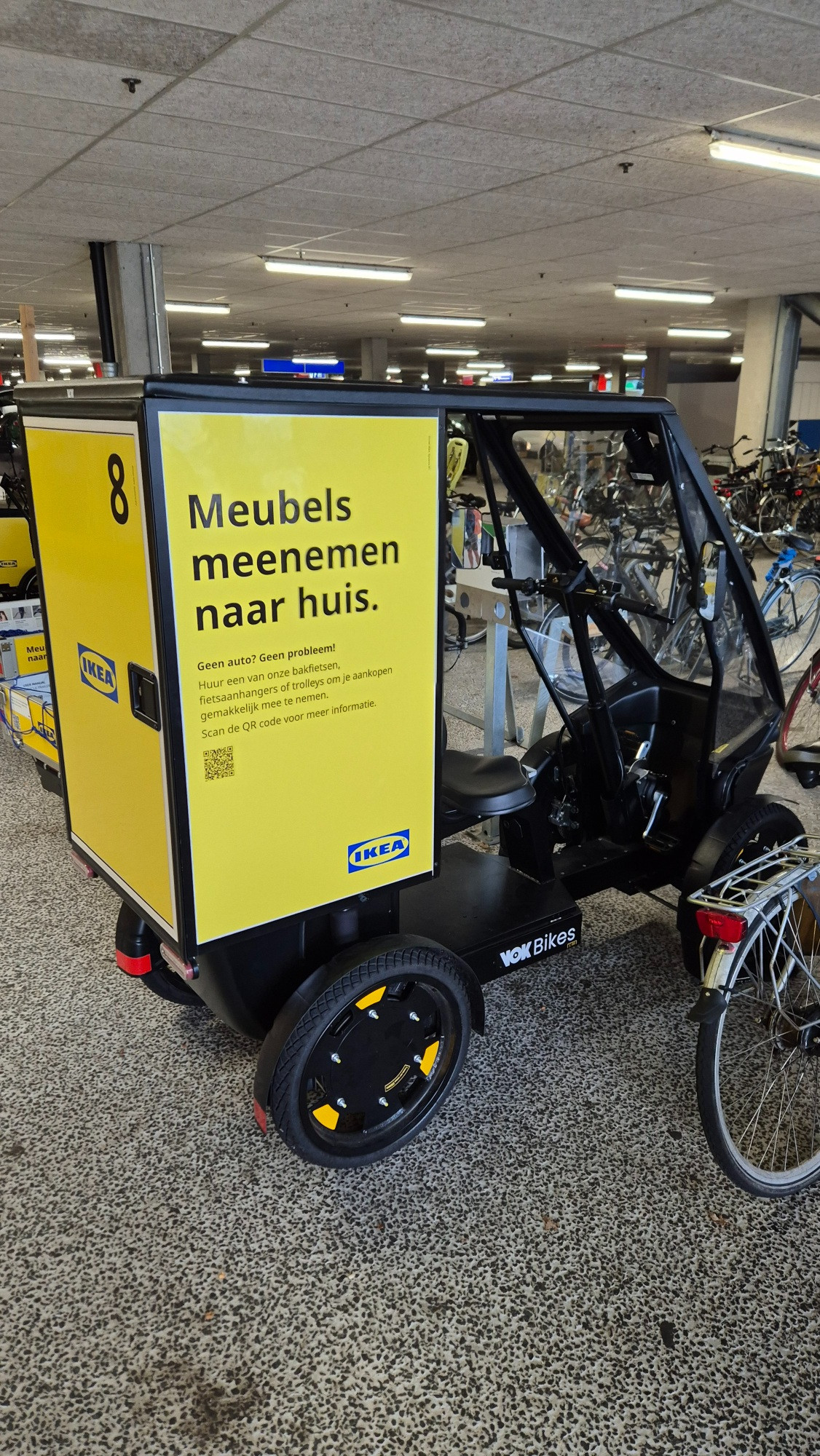 Photo of a covered IKEA cargo bike. The following text appears on the side:

"Take furniture home.

No car? No worries!

Rent one of our cargo bikes, bike trailers, or trolleys to easily transport your purchases. Scan the QR code for more information."