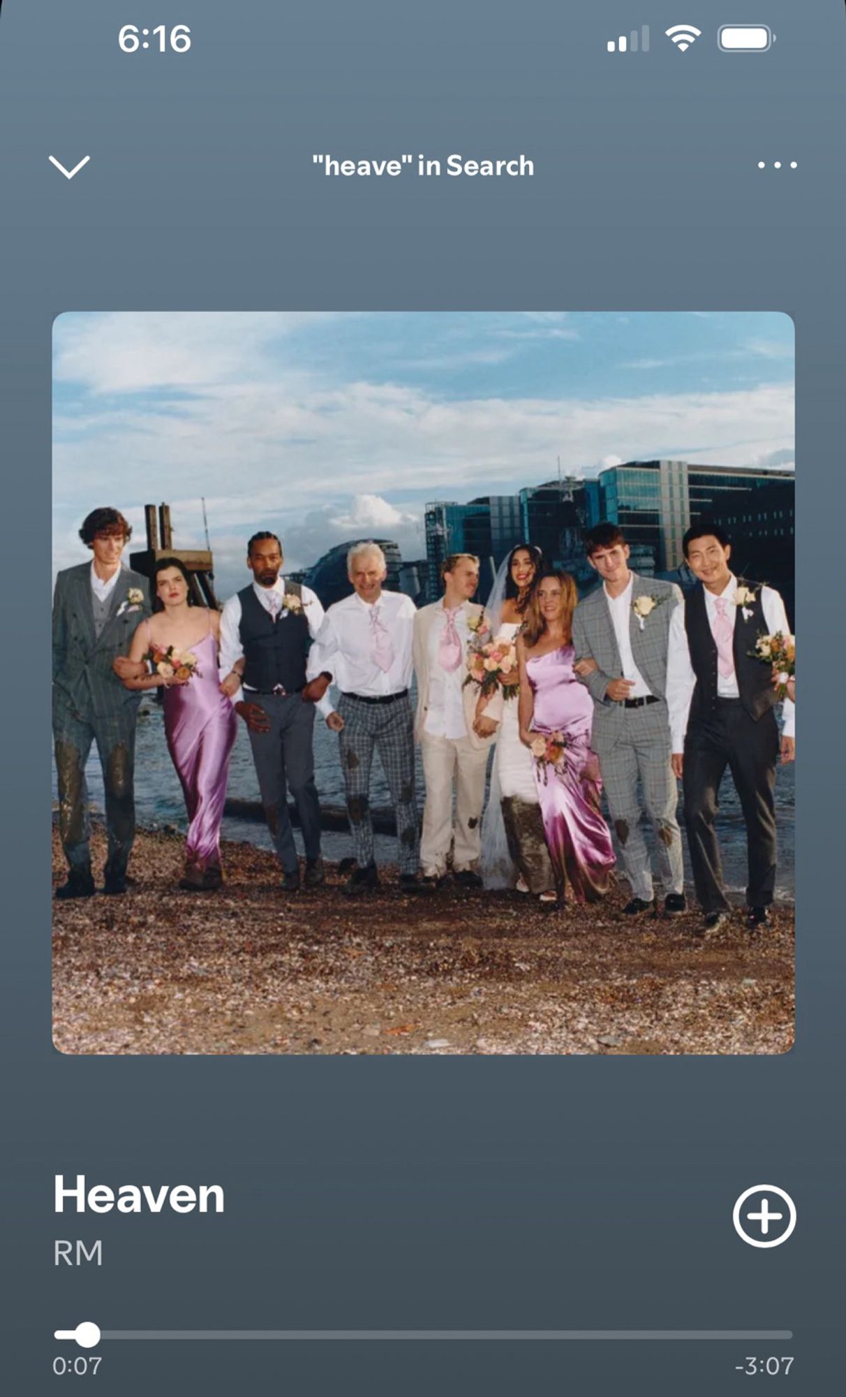 A screenshot of BTS’s RM’s song Heaven playing on Spotify. It shows one of the photos from the photo book from the album Right Place, Wrong Person. A wedding party stands on the beach. They’re all wearing shades of gray and pink and are muddy from the knees down except for RM. he stands on the far right side, perfectly clean, wearing a black suit.