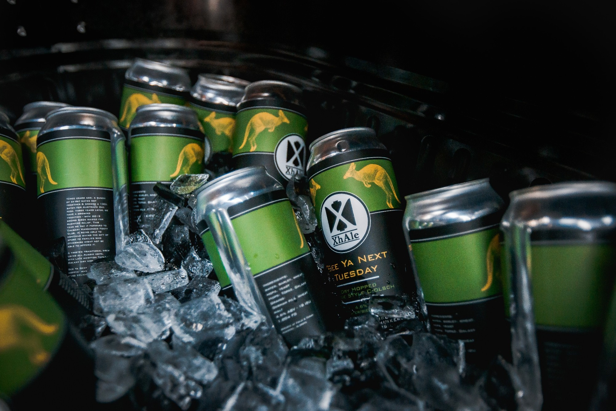 An ice bucket full of cans of a beer called See Ya Next Tuesday, which features a yellow kangaroo and green stripe on a black background.