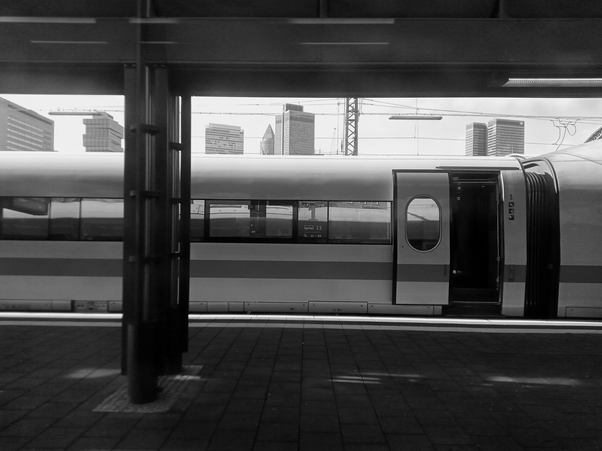 ICE an einem Bahnsteig, schwarzweiß, im Hintergrund frankfurter Hochhäuser