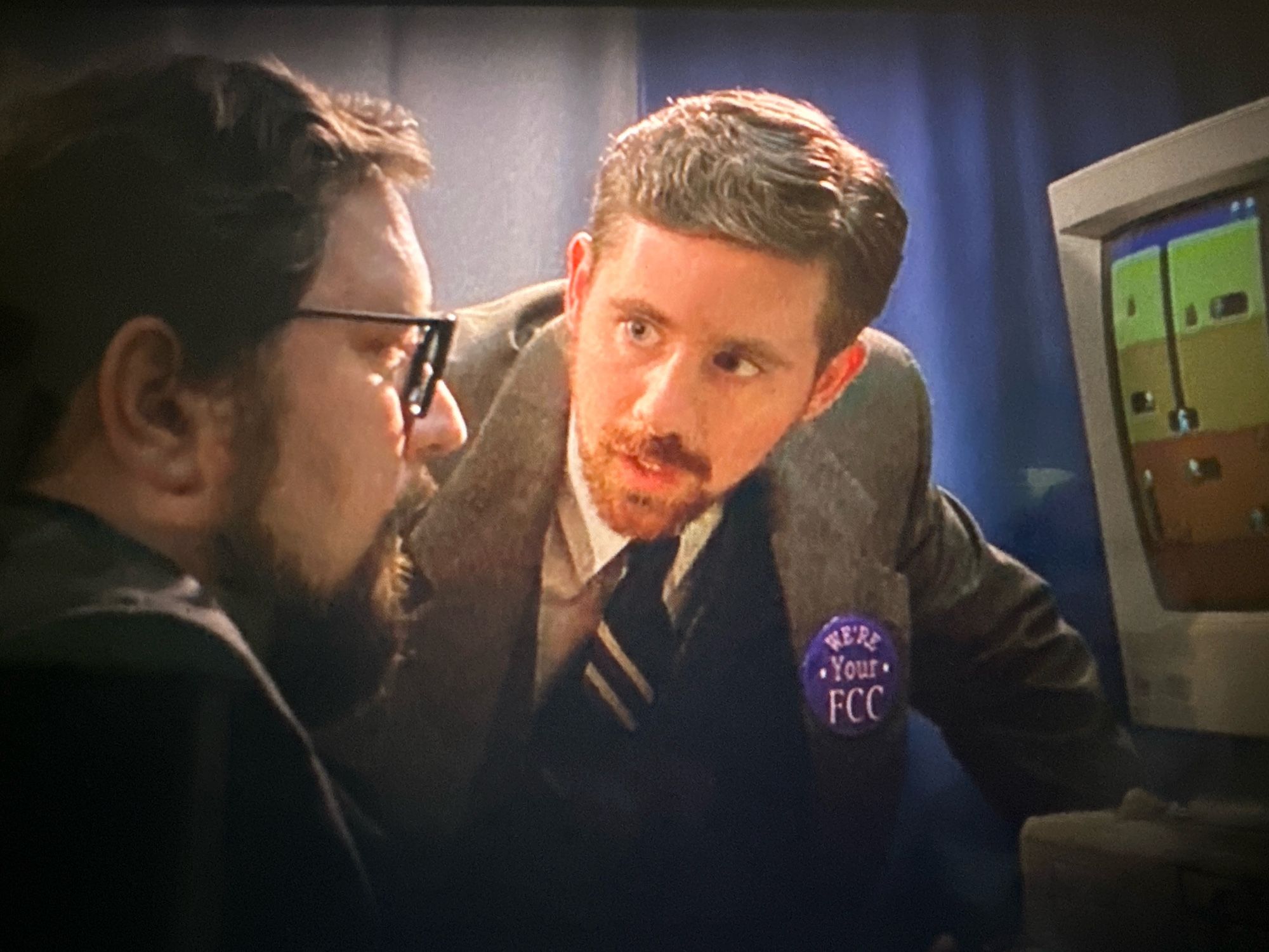 the beardo lone gunmen with a big blue WE’RE YOUR FCC button speaks to his booth mate