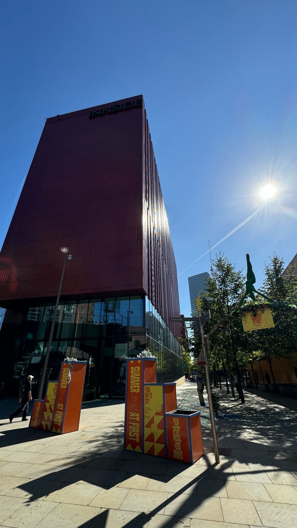 A tall burgundy building in bright bright sun