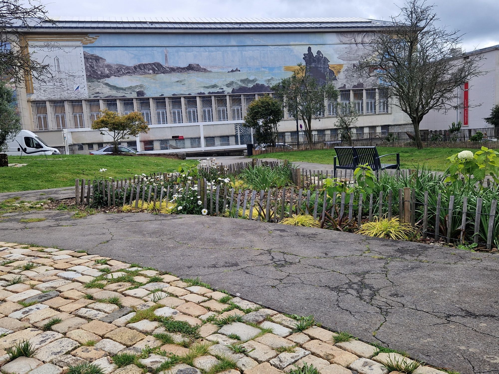 Vue sur le musée des Beaux Arts de Brest
Mur peint : fresque d'un phare sur la côte océanique

Au premier plan, des pavés avec de l'herbe dans les jointures