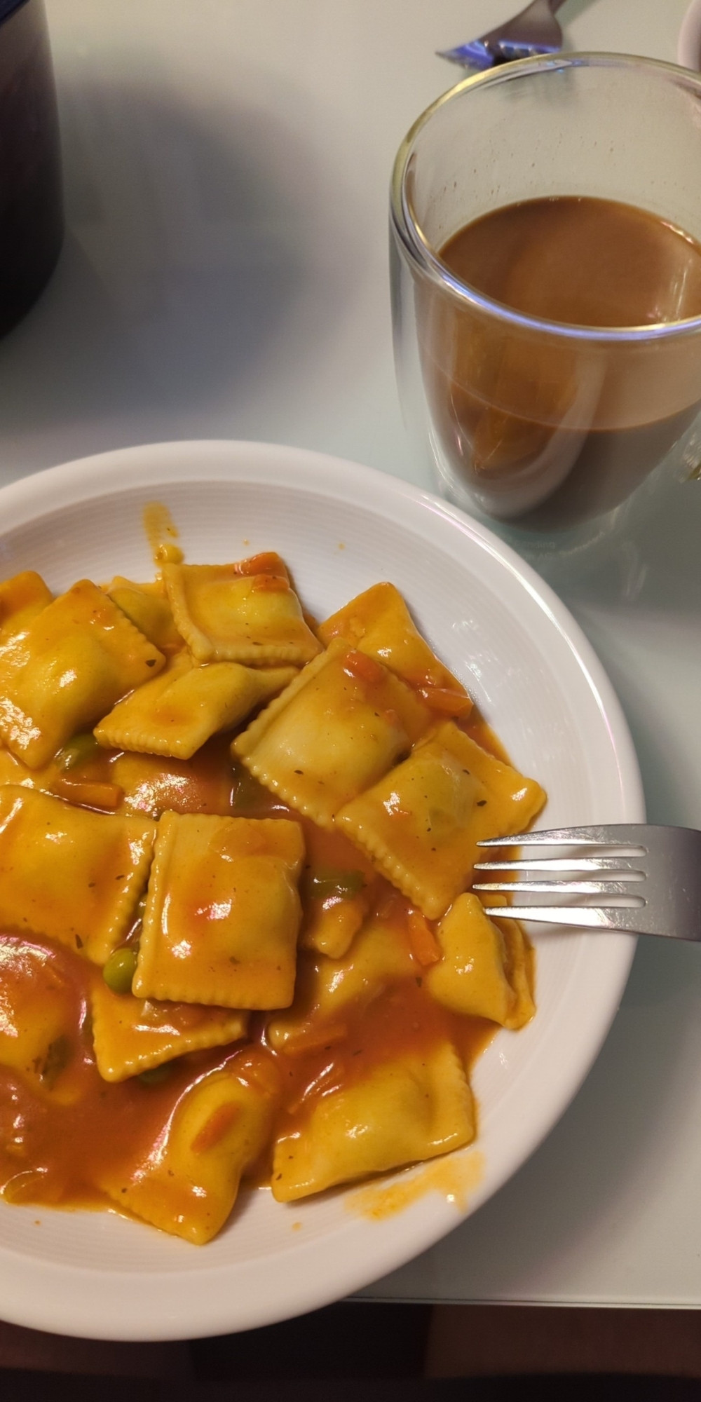 Teller voller Ravioli und eine Tasse aus Glas voller Kakao