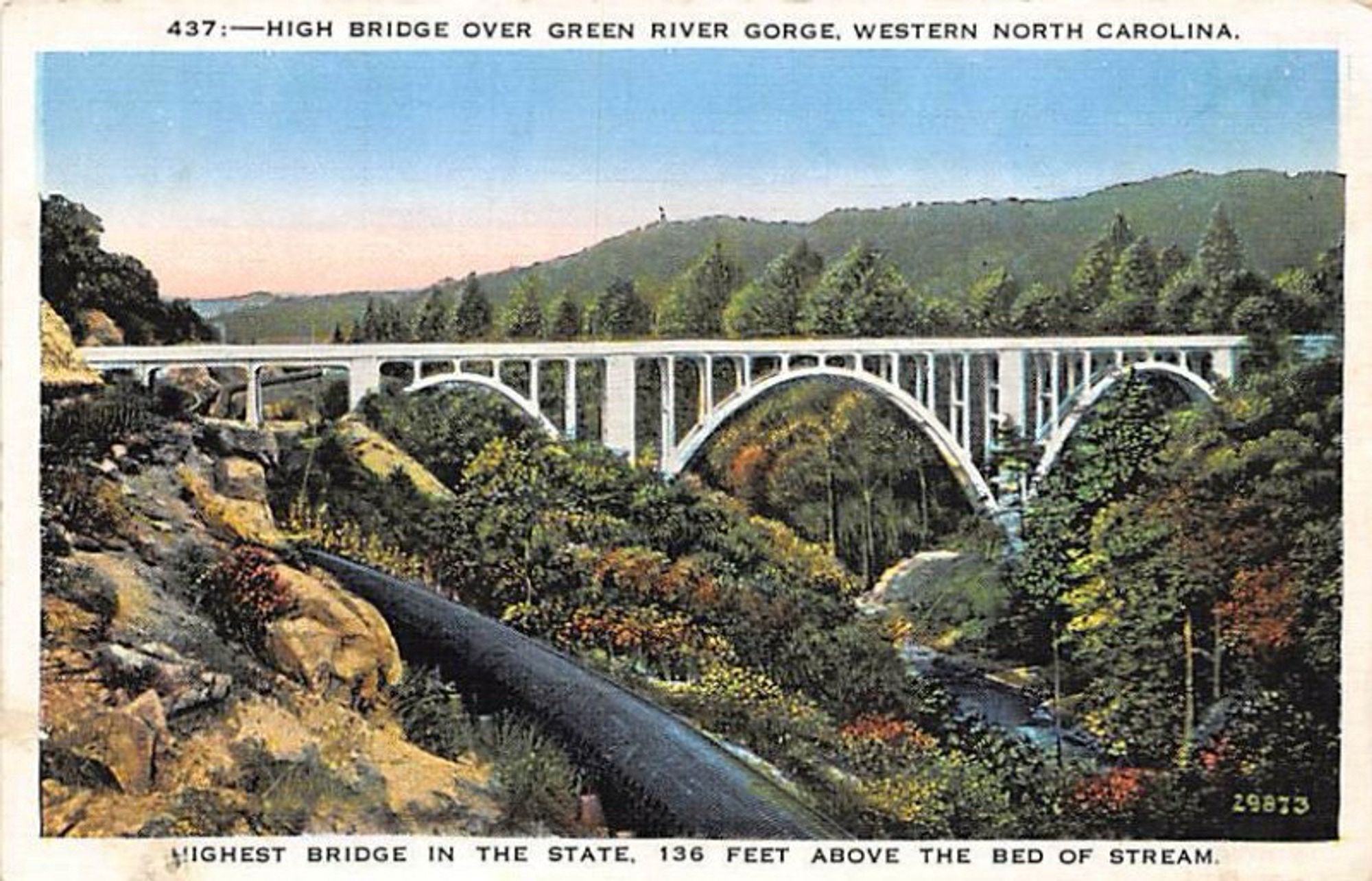 Post card picture of the Green River Gorge Bridge completed in 1972. Image shows a white  bridge in forested, mountainous landscape going over a deep gorge. 3rd highest interstate bridge in the Eastern US. https://www.onlyinyourstate.com/state-pride/north-carolina/peter-guice-memorial-bridge-nc