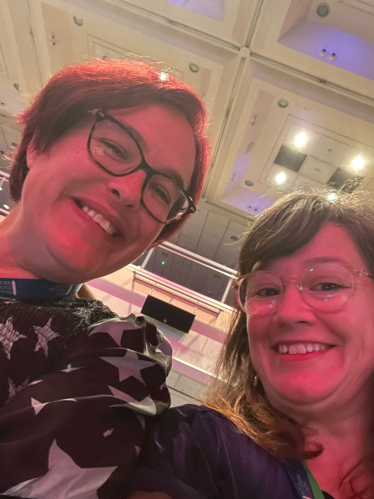 Two beautiful, smiley ladies taking a selfie at conference hall