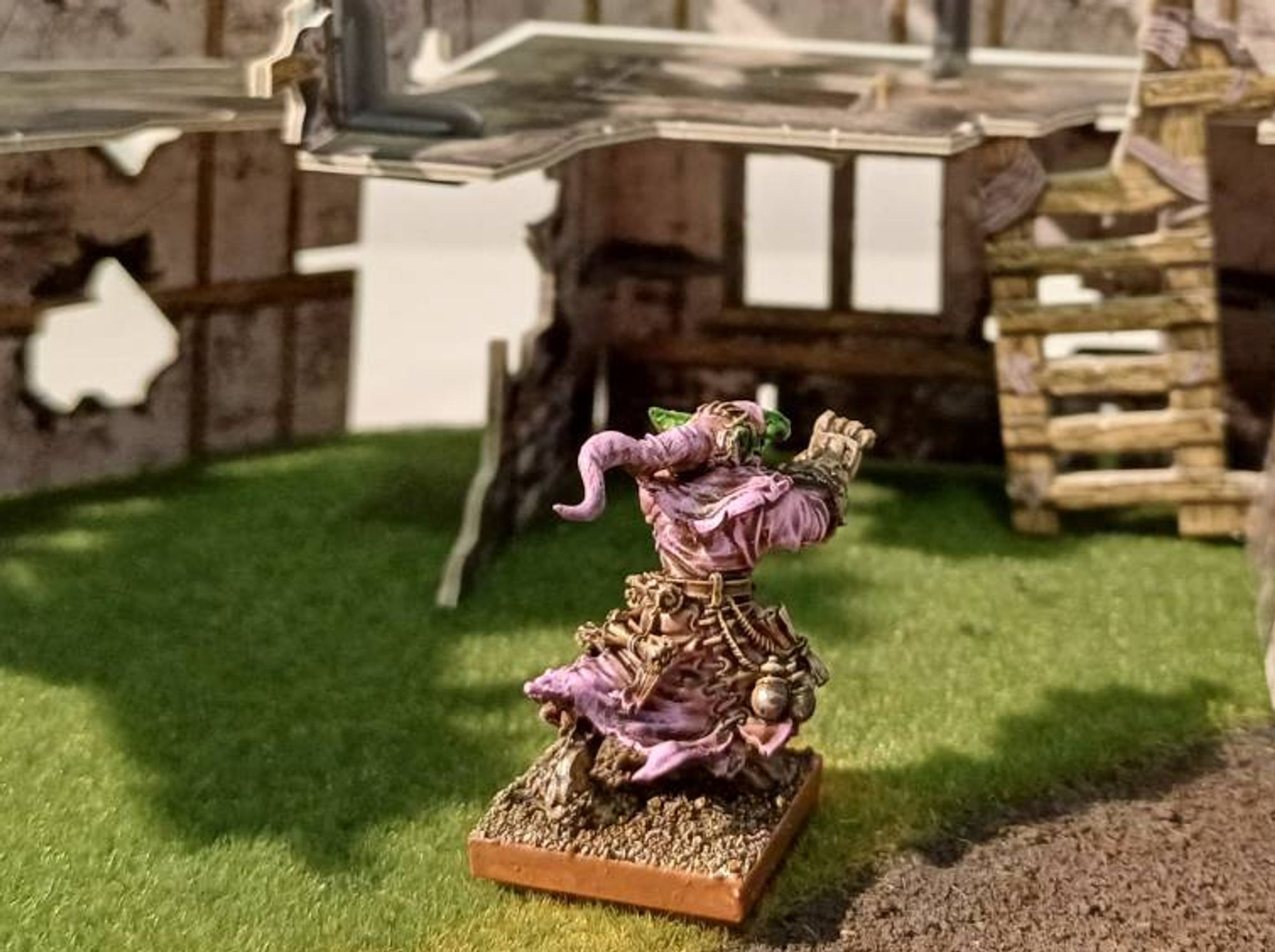 Photo: a goblin wizard in pink robes, his hands in the classic kamehameha/hadoken release position, various baubles and scrolls are visible dangling from his belt; rear view